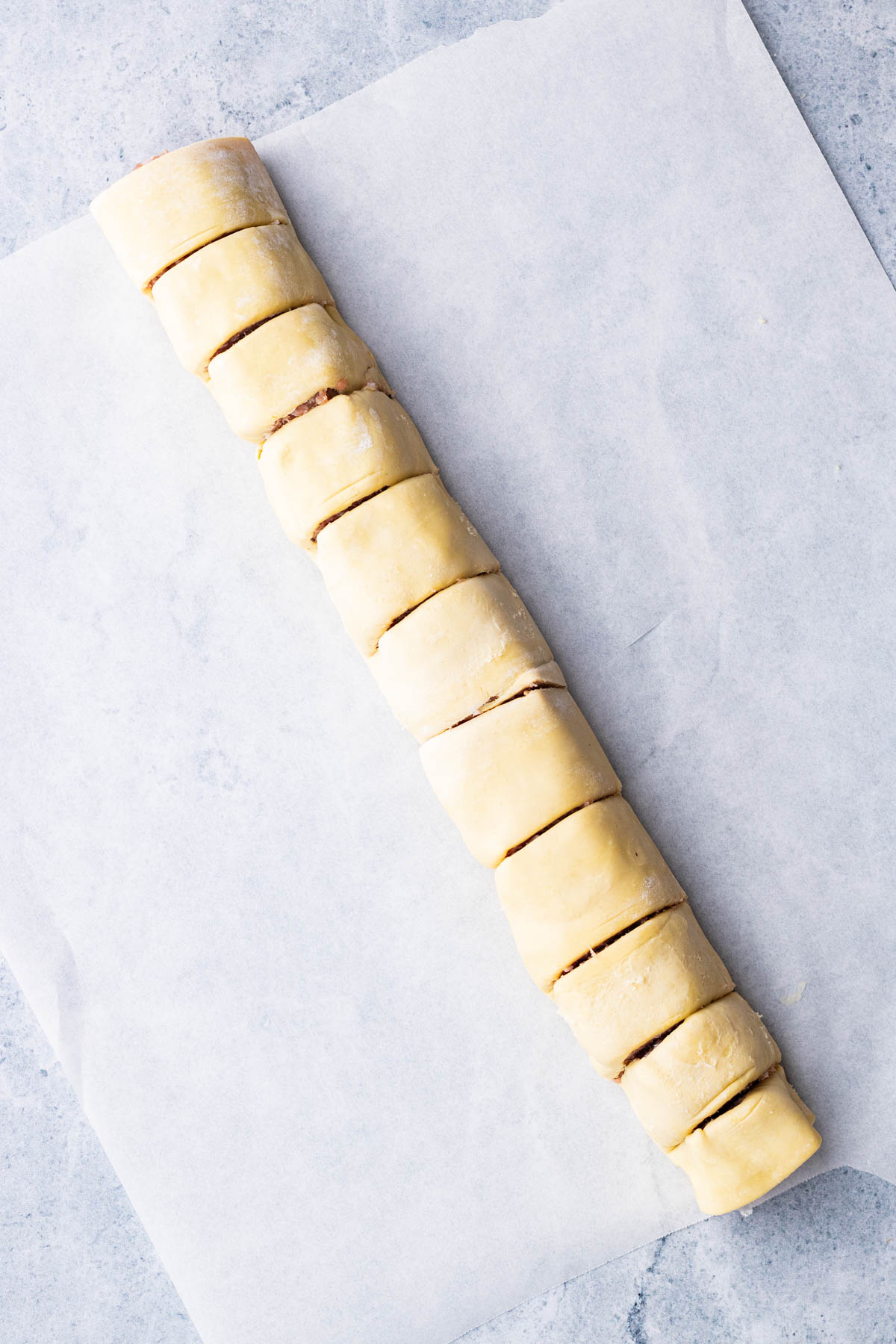 A rolled up log of pork sausage meat in puff pastry then cut into twelve equal pieces.