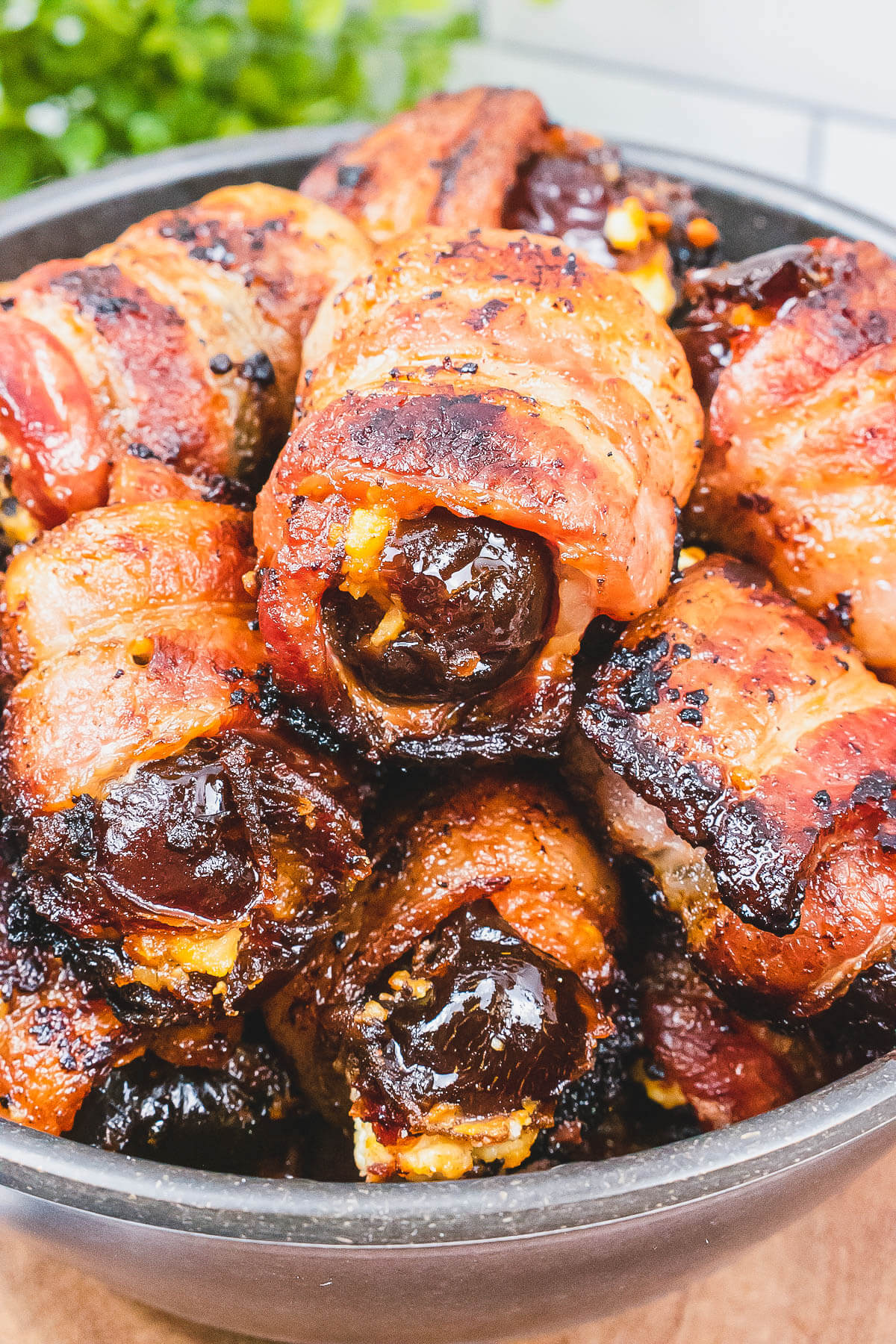Close up photo of glistening bacon wrapped stuffed dates .