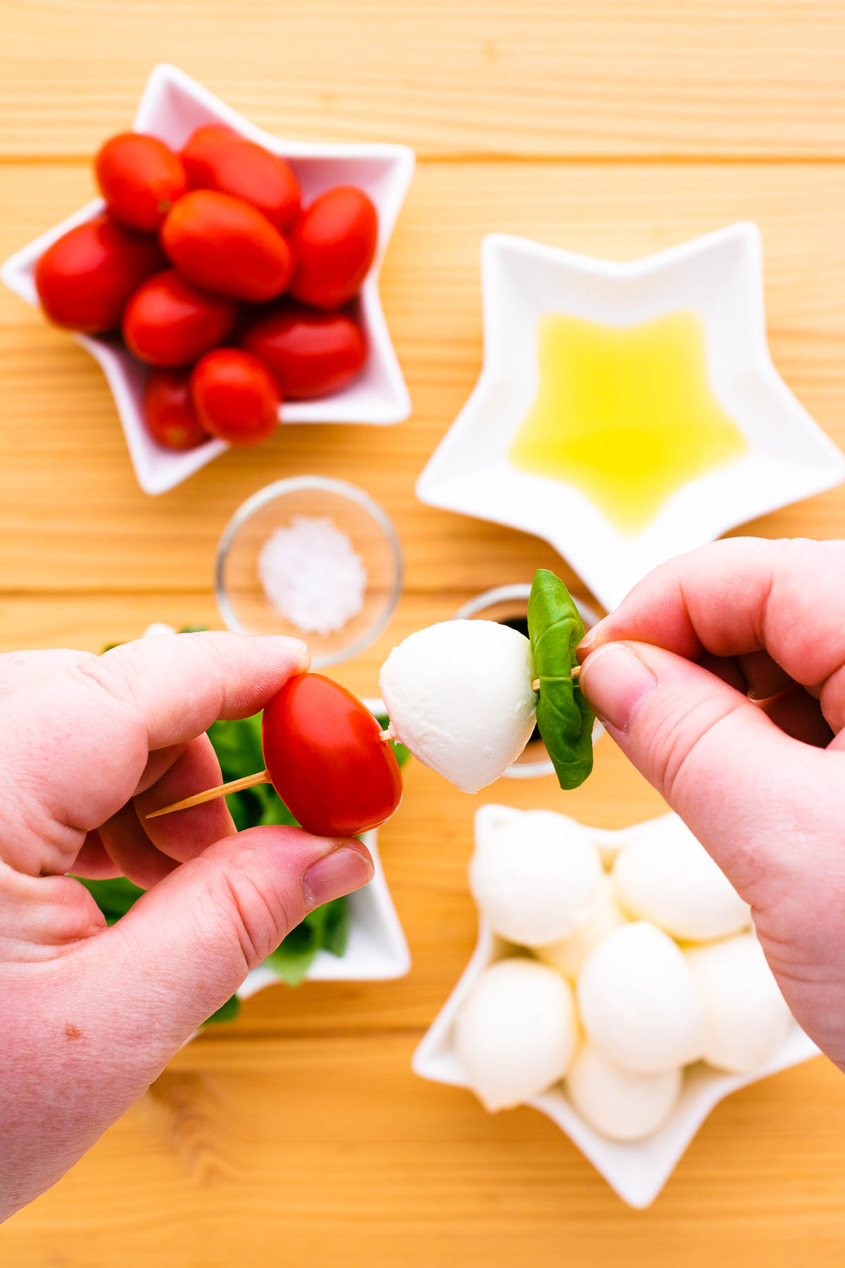 Process photo showing how to thread caprese salad ingredients onto a wooden skewer.