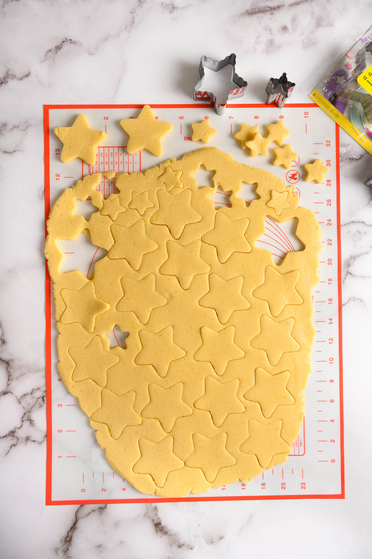 Rolled dough with cut out star shaped cookies of varying sizes.