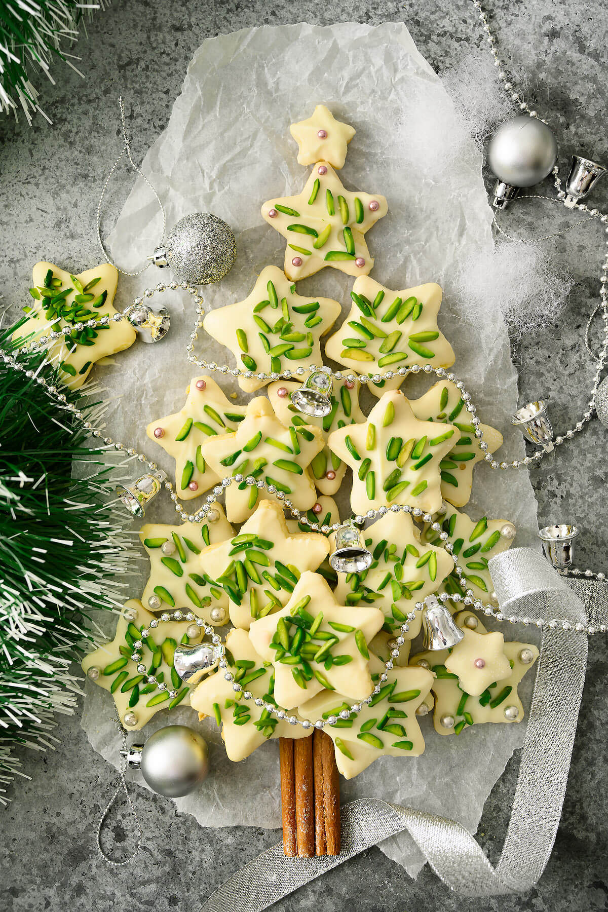 Sugar star cookies decorated with pistachios and silver dragées arranged as a Christmas tree..
