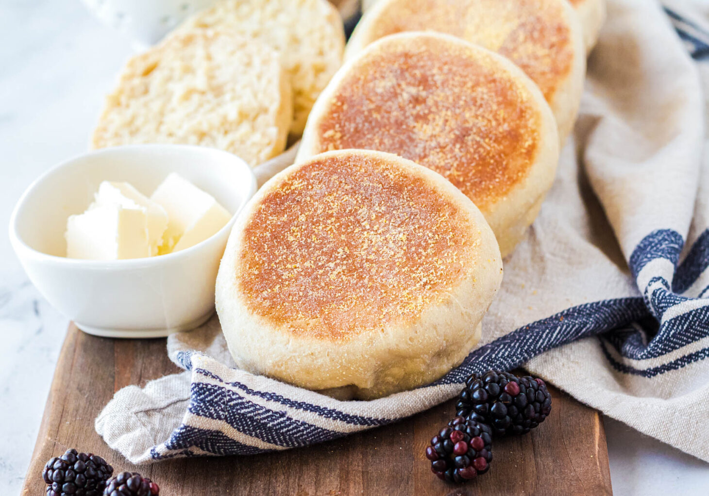 A breakfast table set with golden English Muffins, butter, and jam.