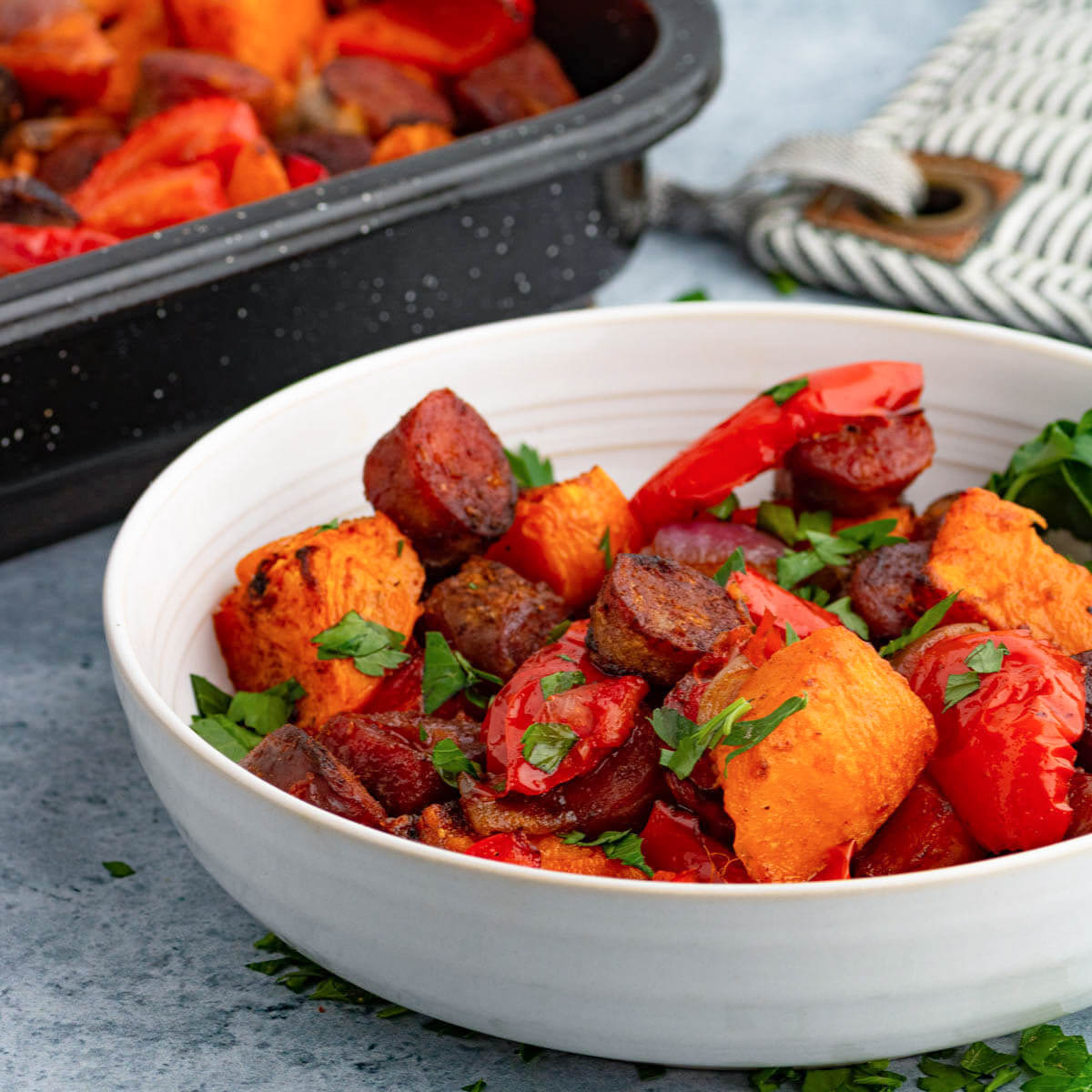 A white bowl filled with brightly coloured chorizo sausage and veggies.