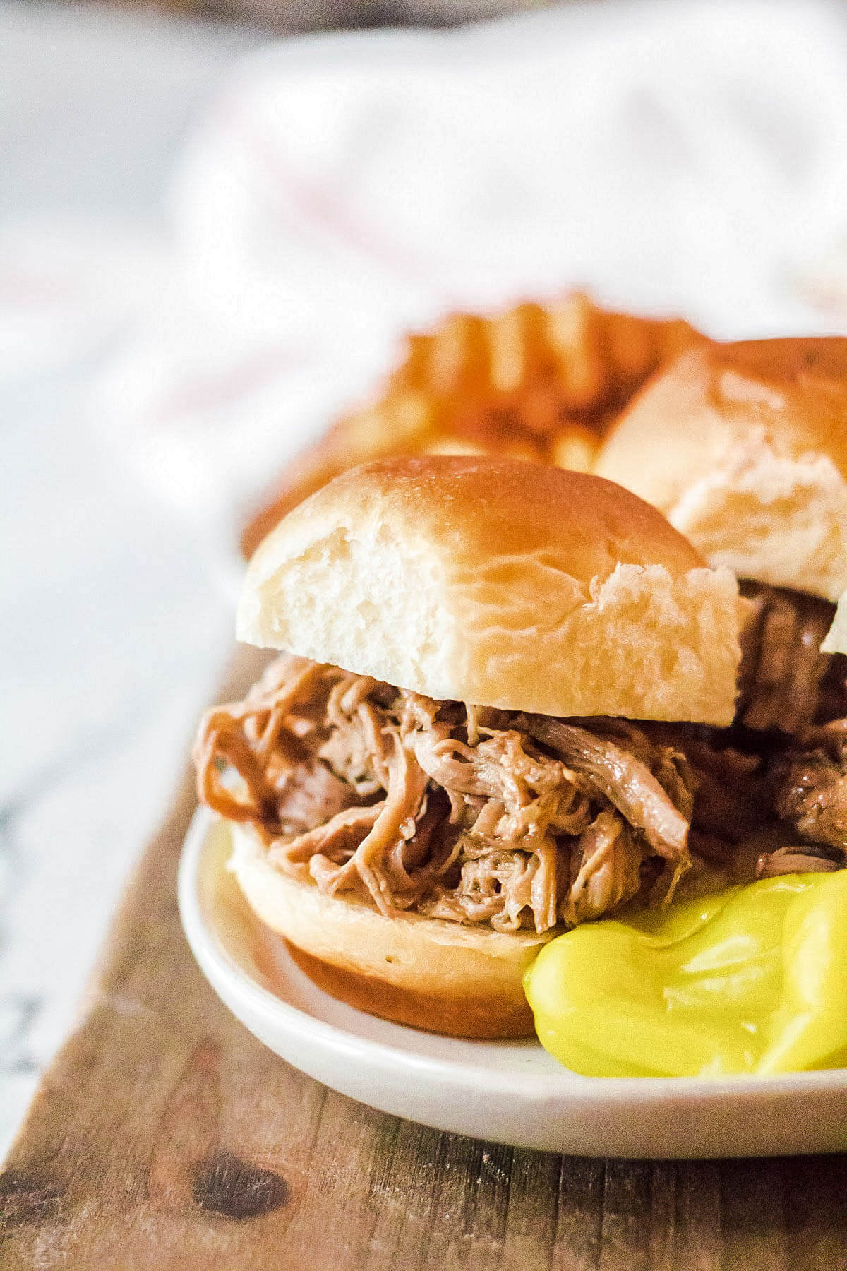 One bun filled with shredded Mississippi Pork Roast on a white plate.