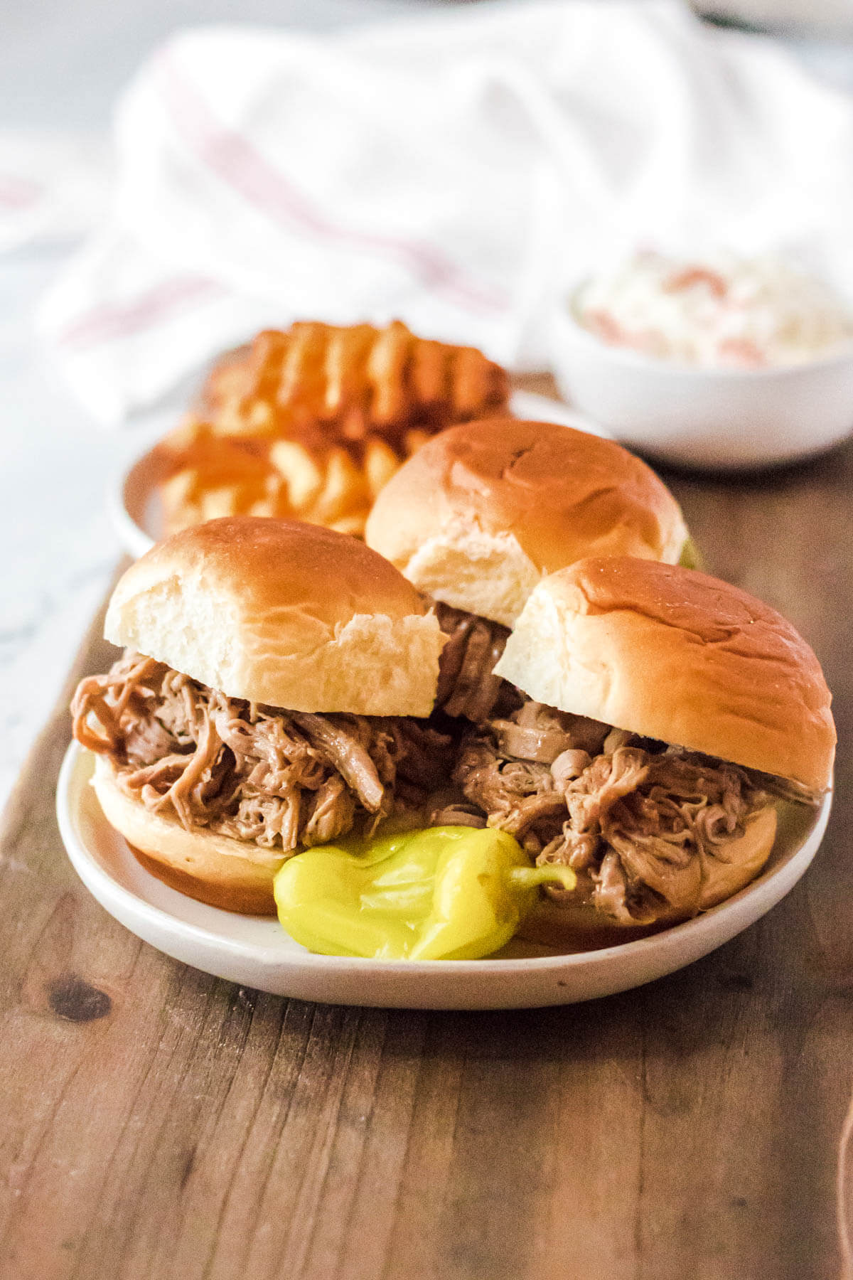 Three buns filled with shredded Mississippi Pork Roast on a white plate.