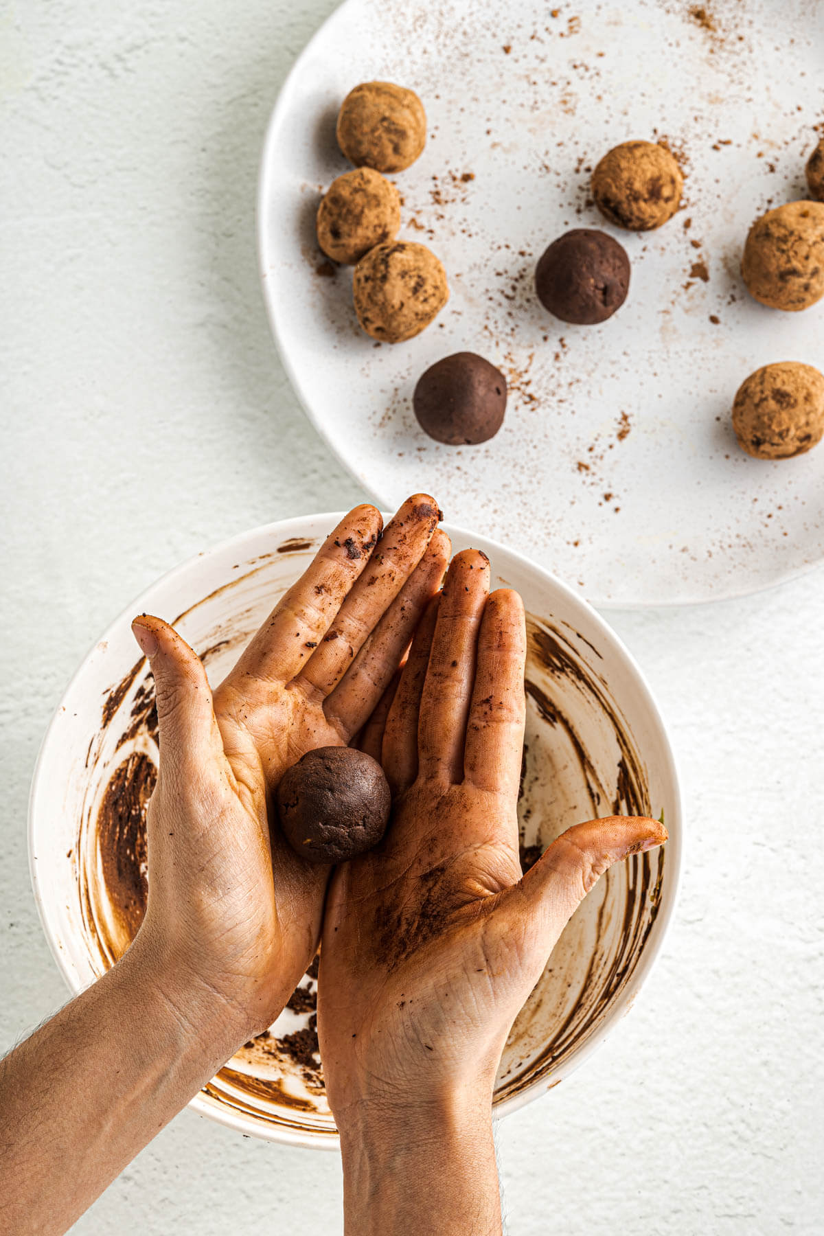 Process shot of a pair of hands rolling a chocolate truffle.