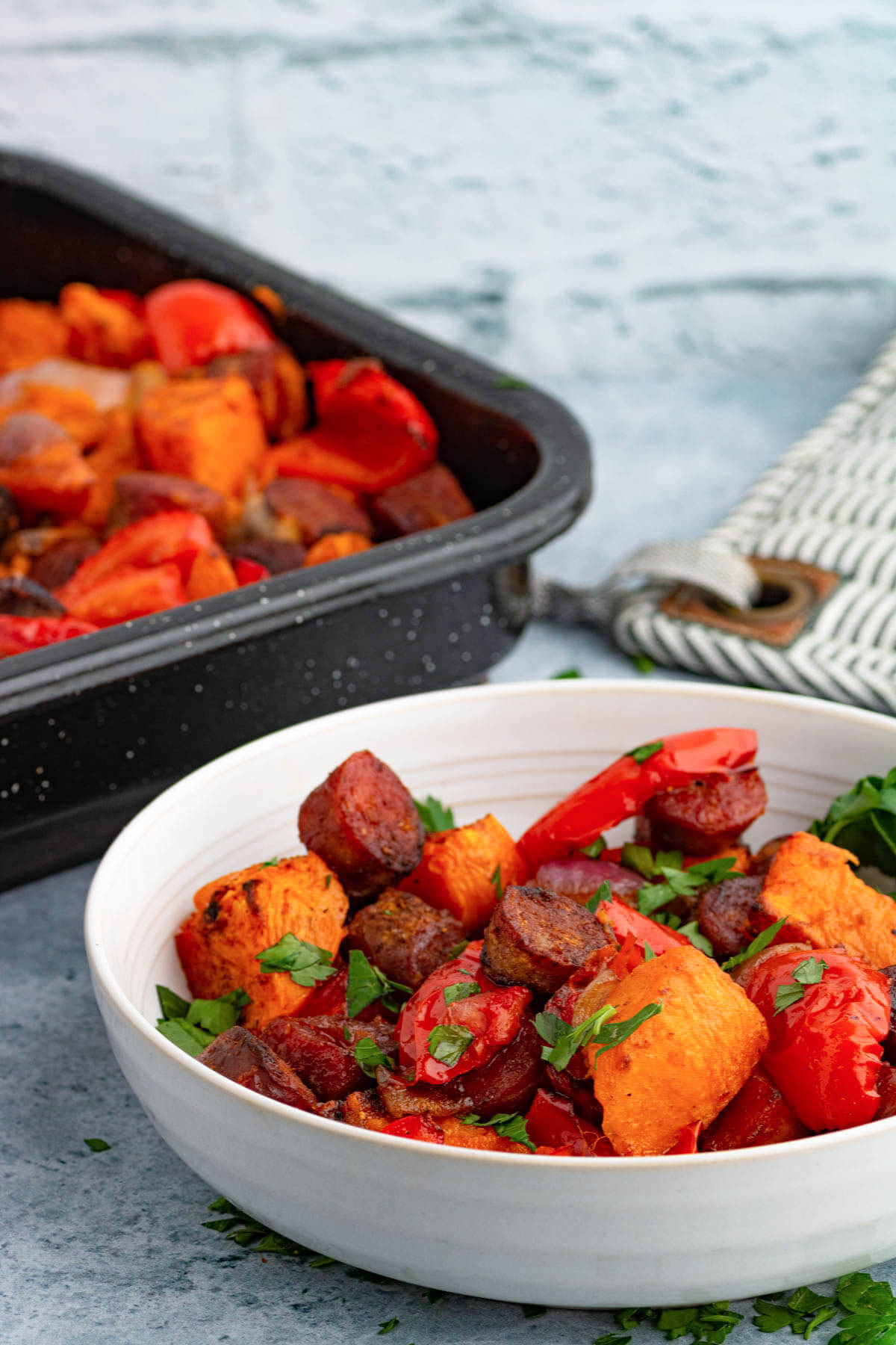 A white bowl filled with brightly coloured chorizo sausage and veggies.
