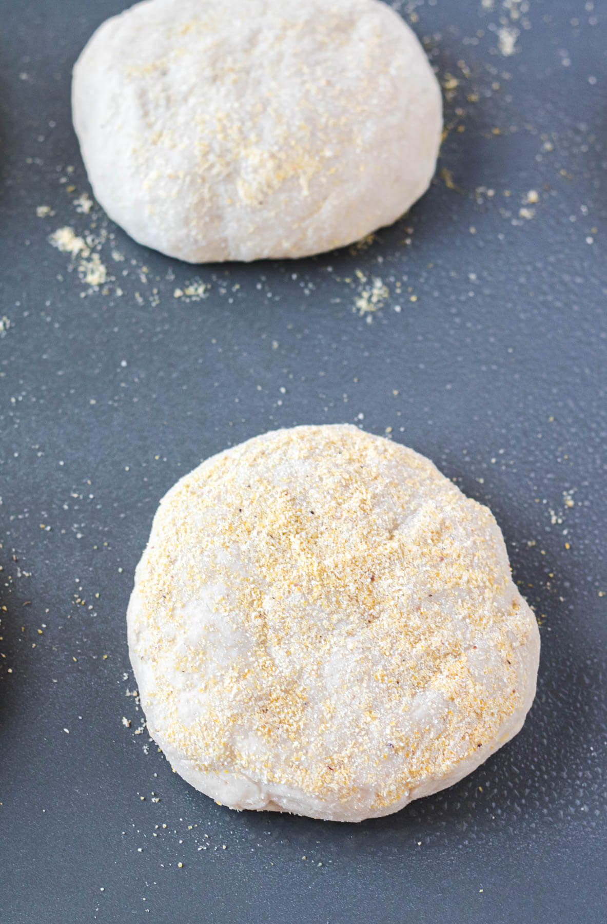 Process shot for English muffin recipe featuring shaped two proofed English Muffins, ready for the griddle.