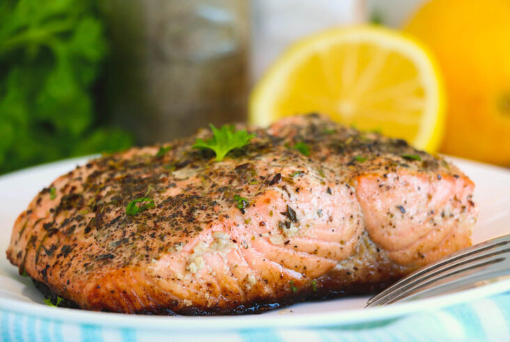 A perfectly cooked skin on cast iron salmon with lemon and herbs on a plate.