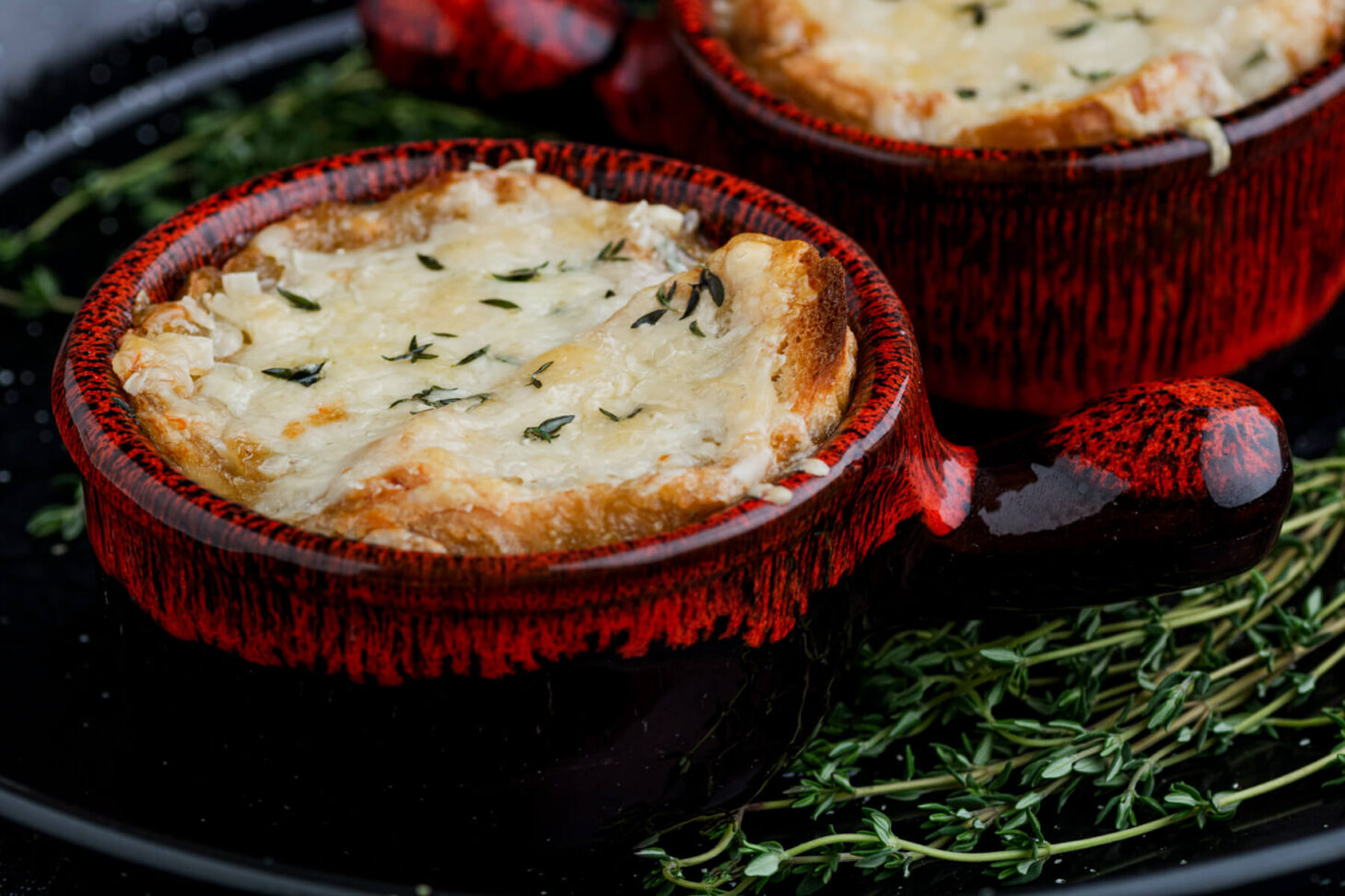 One cheese topped bowls of French Onion soup in stunning pottery soup bowl.