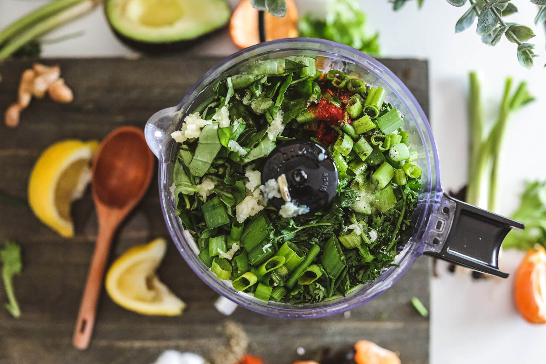 A food process full of fresh herbs and ingredients for Green Goddess Dressing.