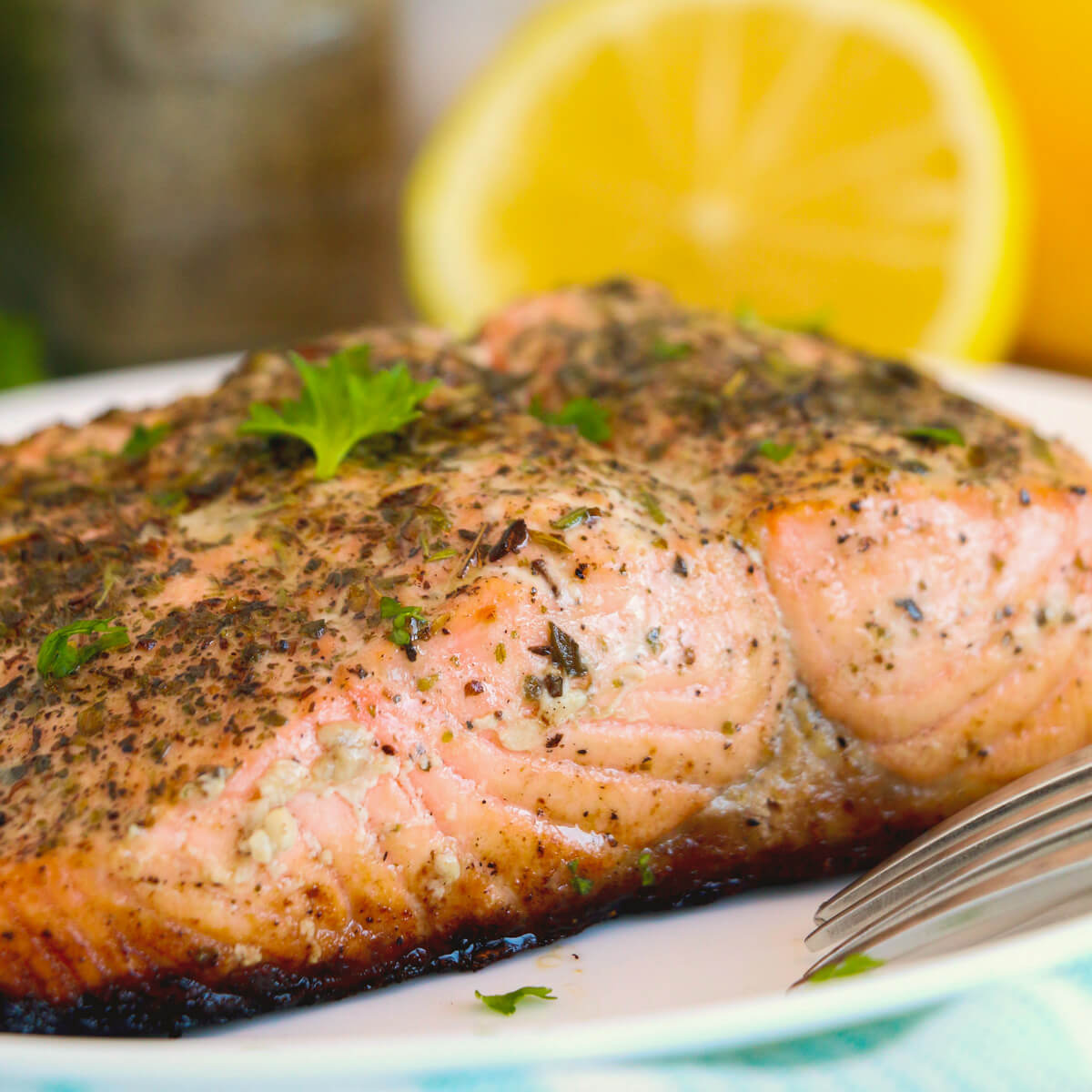 A perfectly cooked skin on cast iron salmon with lemon and herbs on a plate.