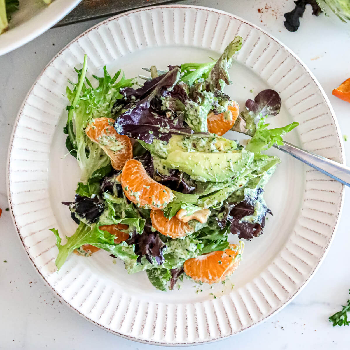 A colourful Spring Mix Salad with Green Goddess Dressing on a white plate.