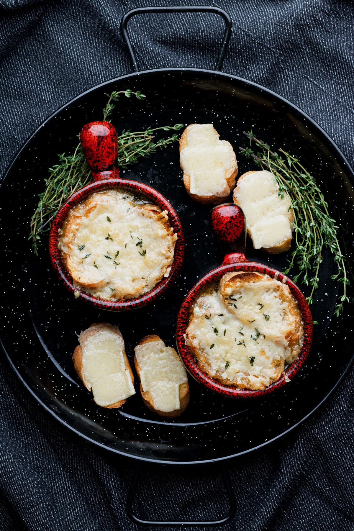Two cheese topped bowls of French Onion soup in stunning pottery soup bowls.