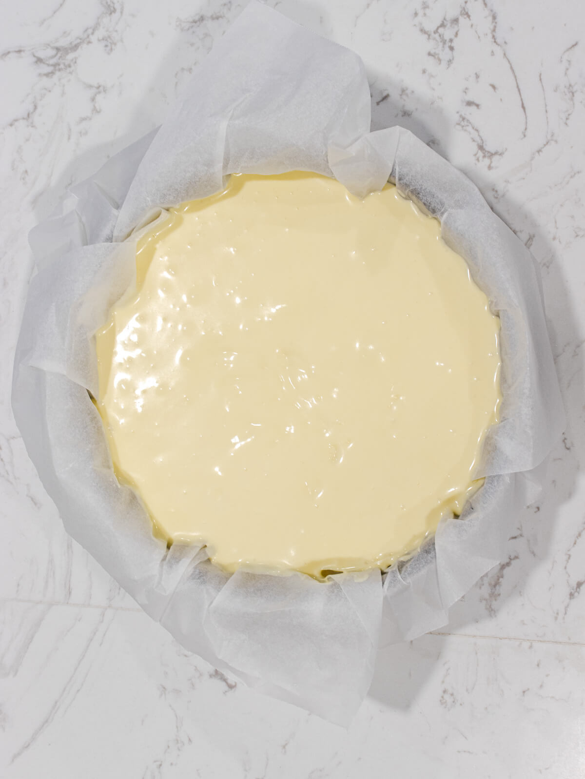 Creamy cheesecake batter in a parchment lined springform pan.
