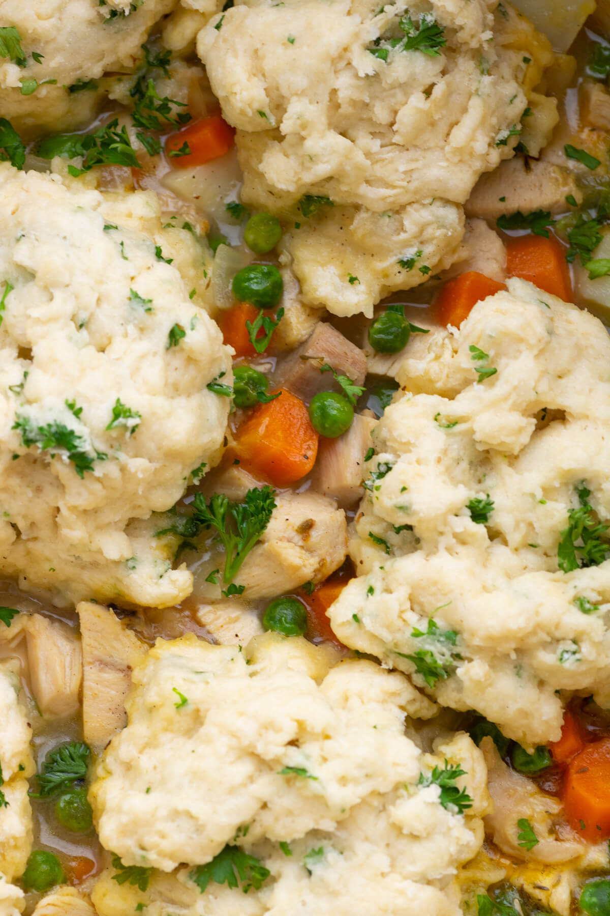 Close up of fluffy flour dumplings in a large pot of chicken stew.