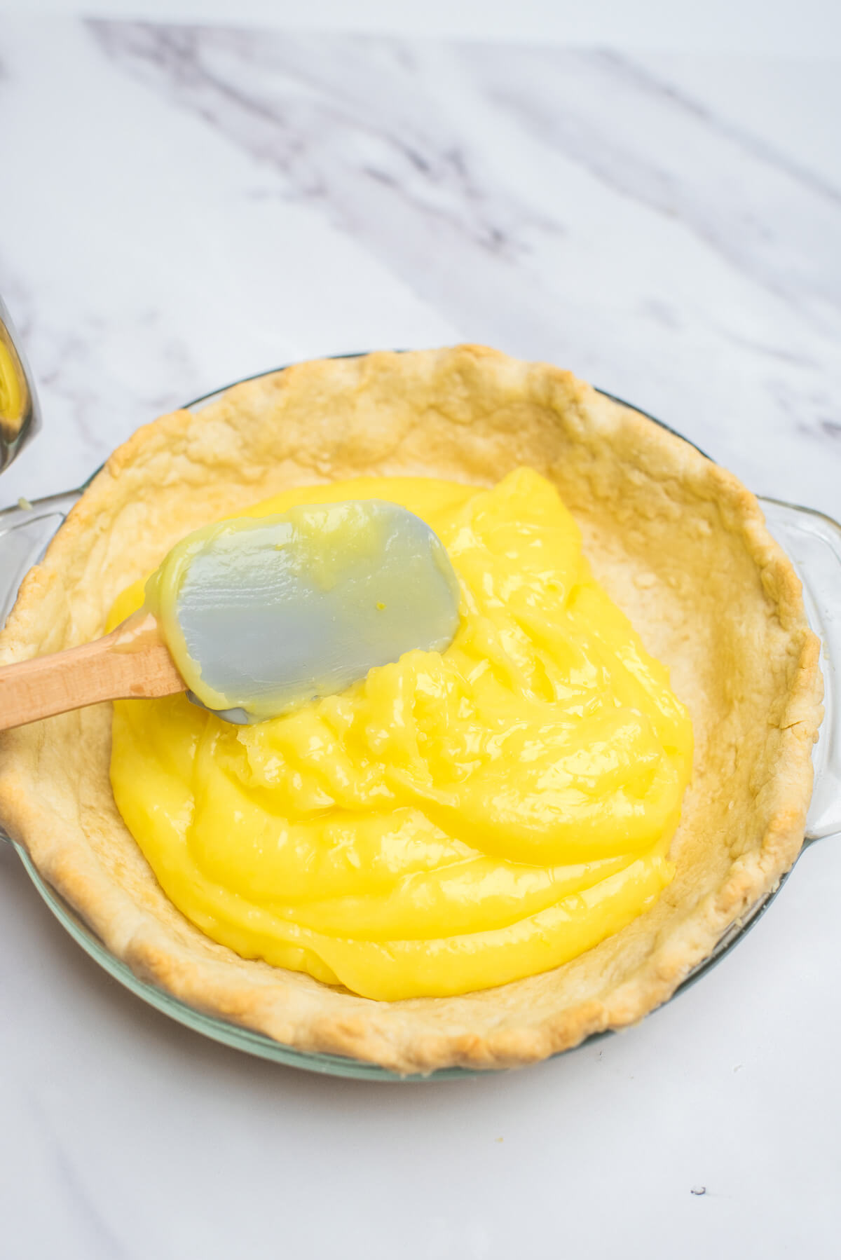Spreading lemon pie filling in a pre baked pastry shell.