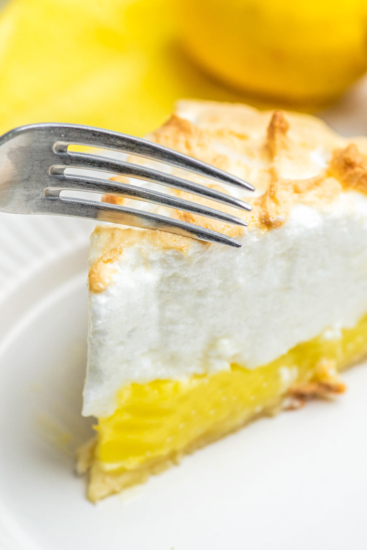 A fork about to cut into a slice of lemon meringue pie.