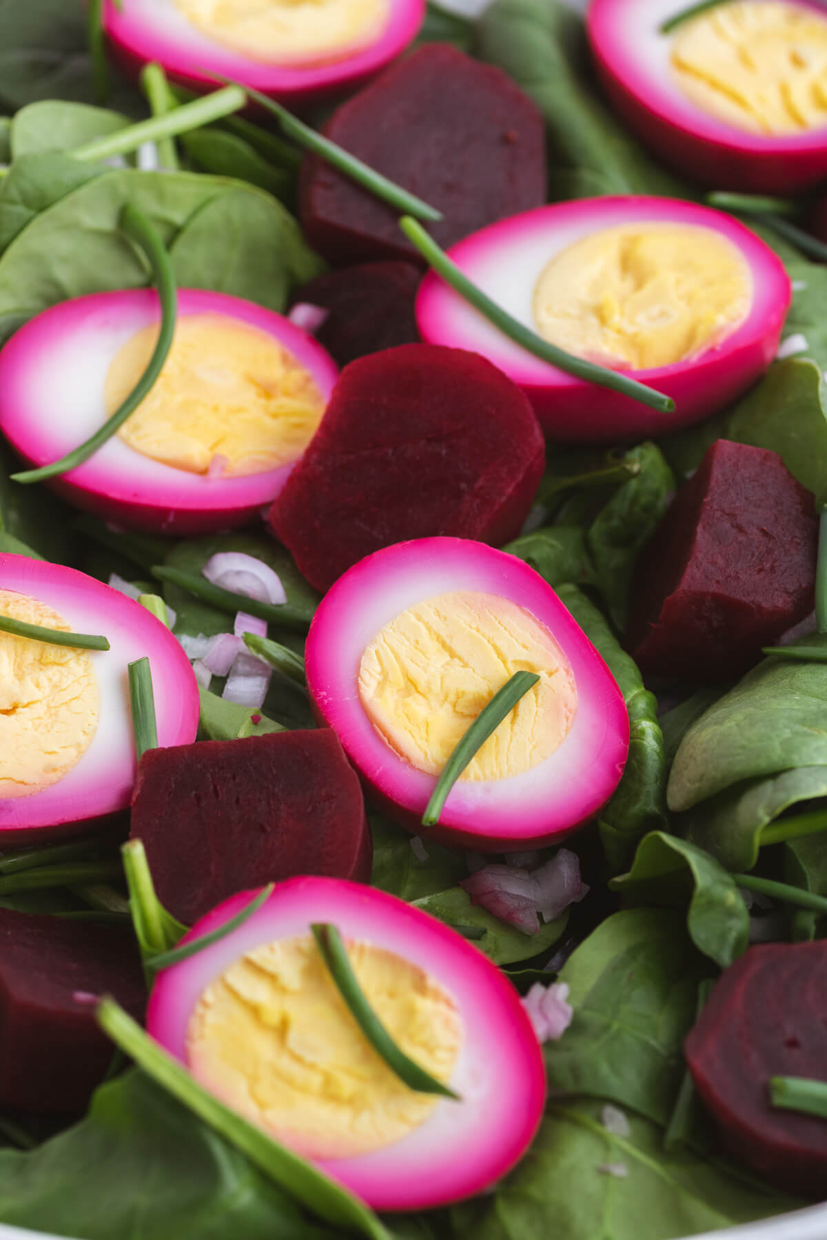 Close up of pickled beets, bright pink eggs and spinach salad