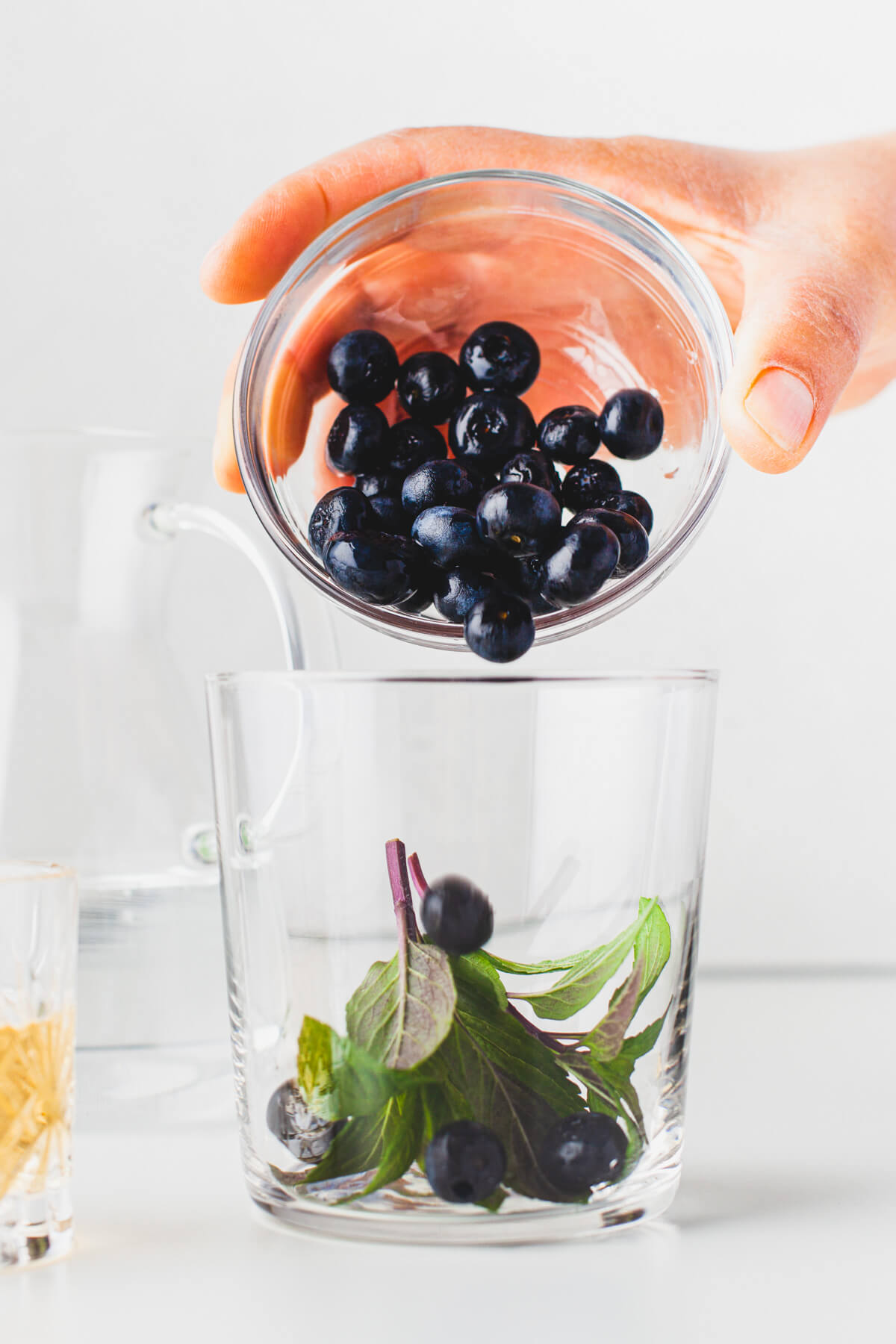 Pouring fresh blueberries into a highball glass.