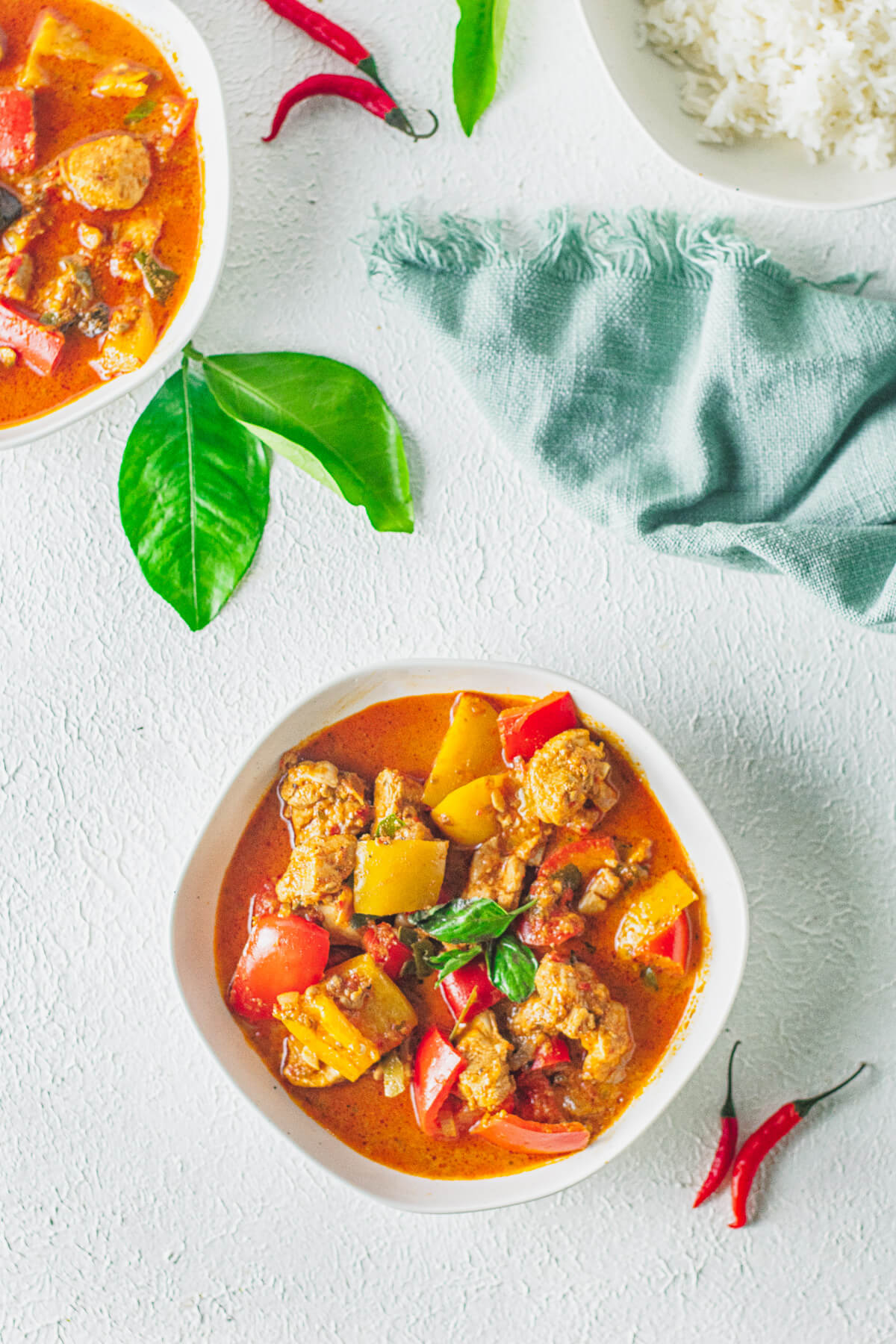 A bold red Thai Panang Chicken Curry with vegetables in a white bowl.