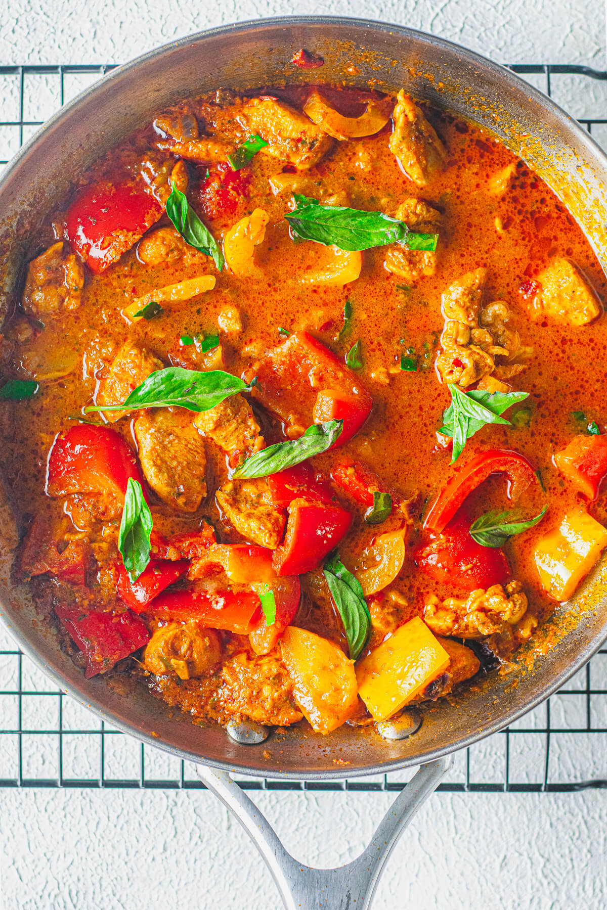 A bold red Thai Panang Chicken Curry with vegetables in a skillet..