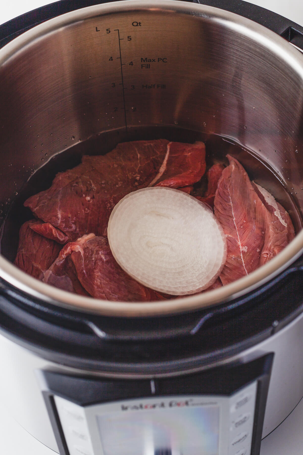 Raw beef and an onion ready to be cooked in an Instant Pot.
