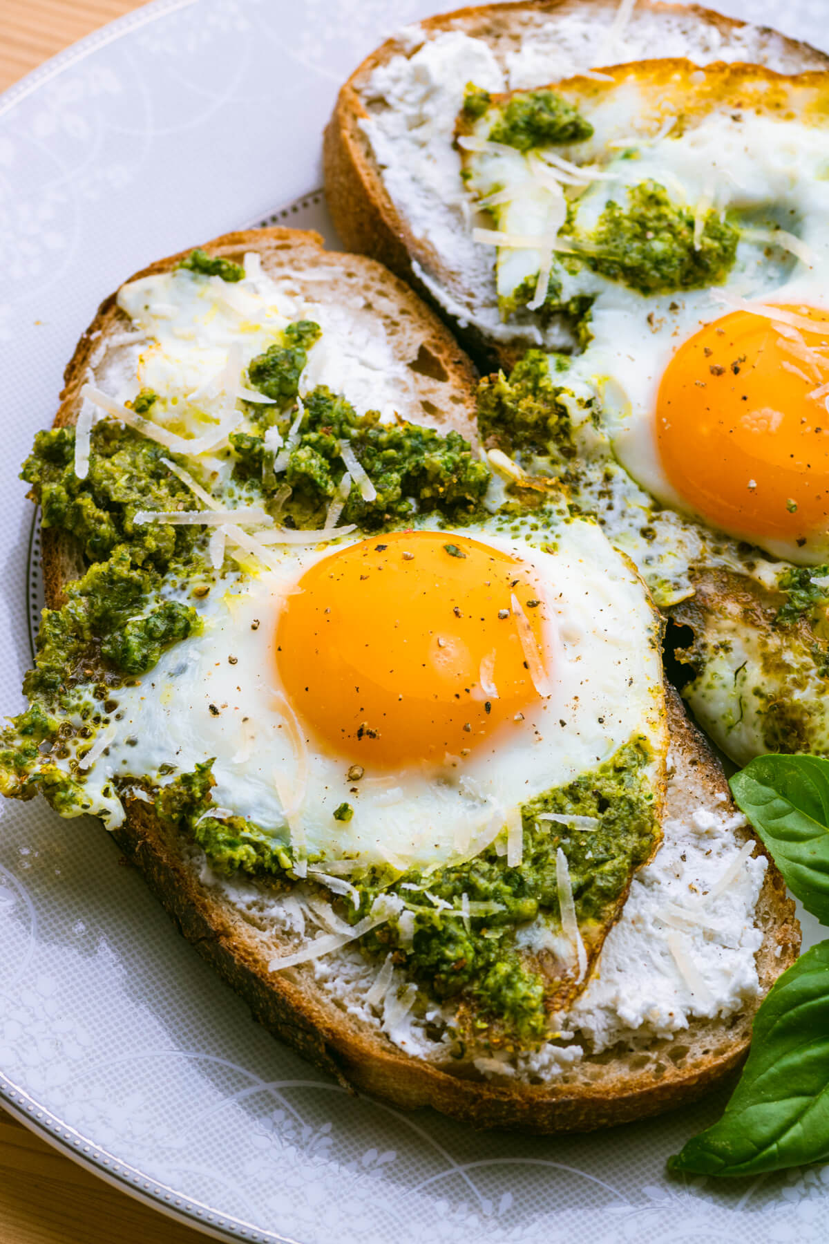 Fried Pesto Eggs on toast with sunny side up yellow egg yolks and vibrant green basil pesto.
