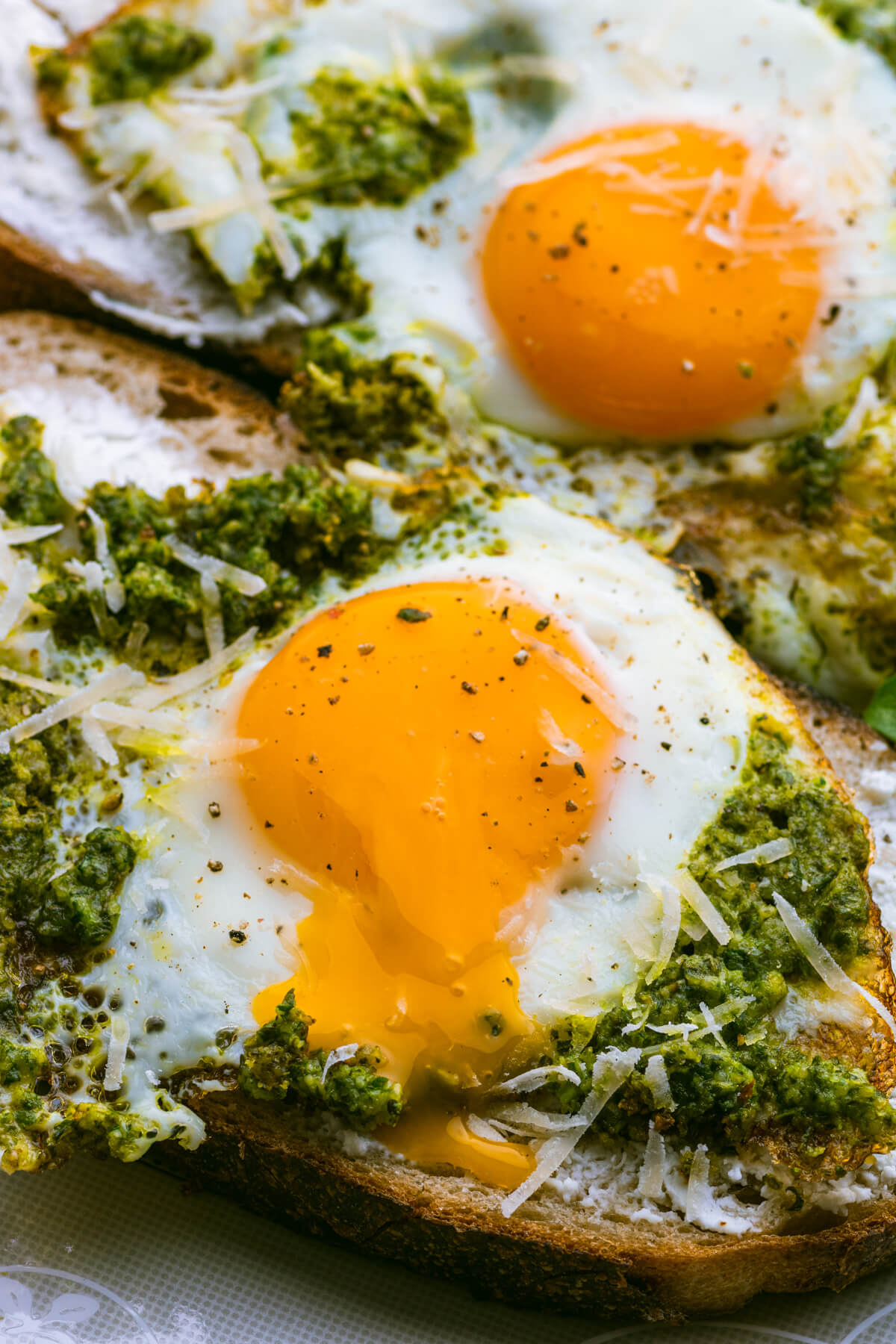 A runny egg yolk oozes over top of the green pesto on a pesto egg toast.