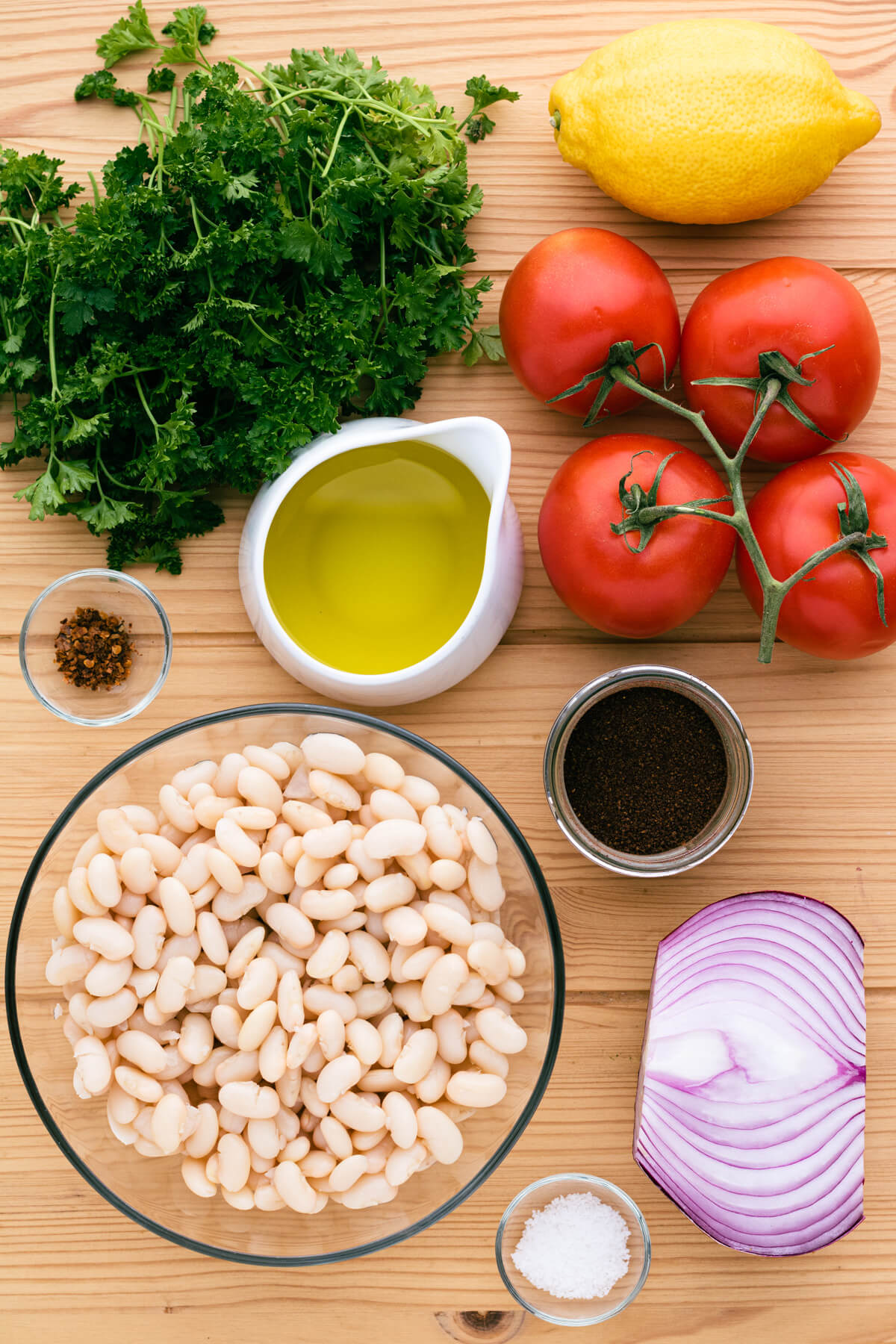 Ingredients for Piyaz; a white bean salad with tomatoes, red onion, and curly parsley.