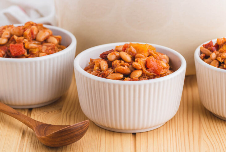 Three bowls filled with chipotle pinto beans with peaches and tomatoes.