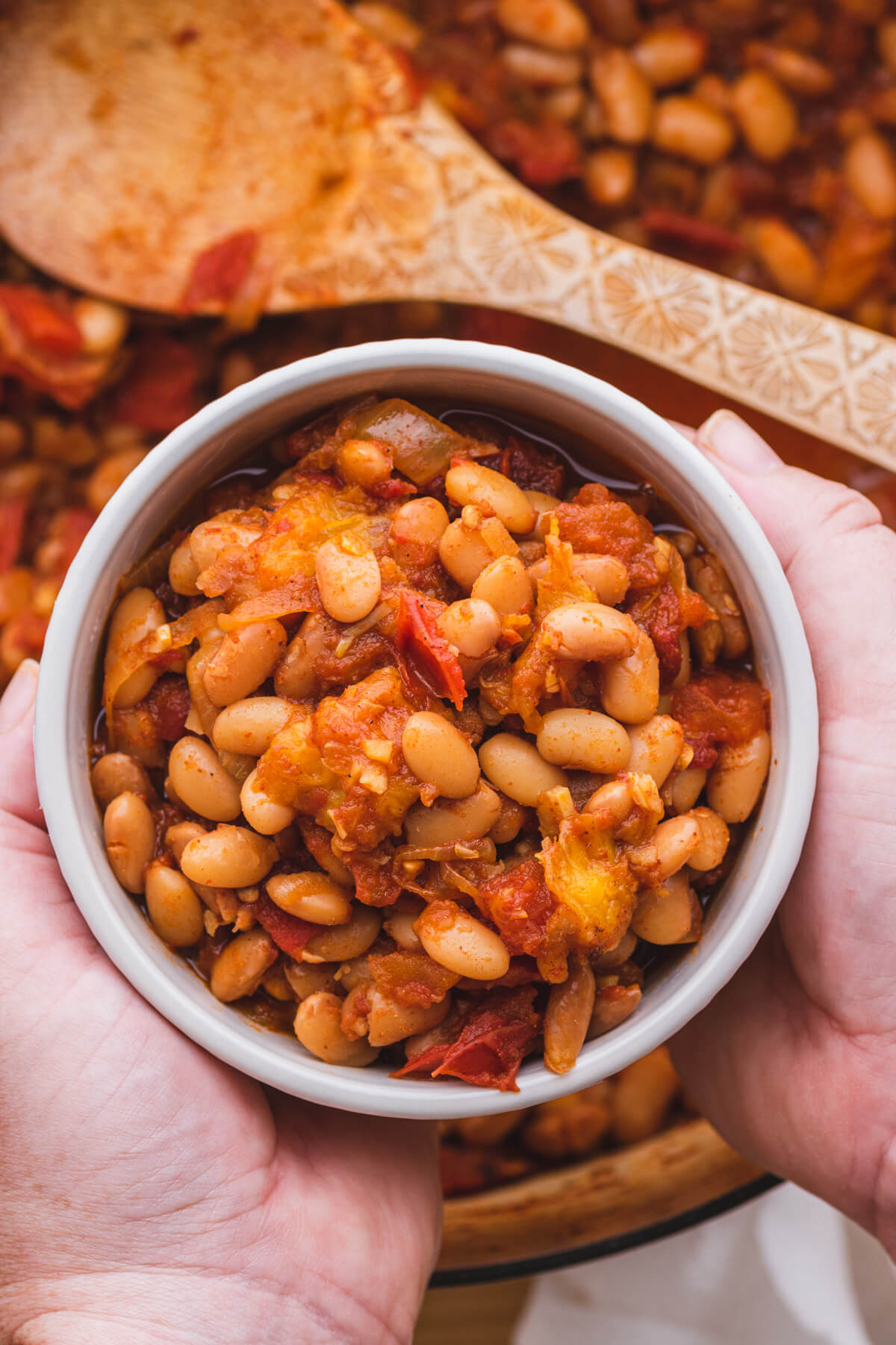 Two hands around a bowl of chipotle pinto beans.