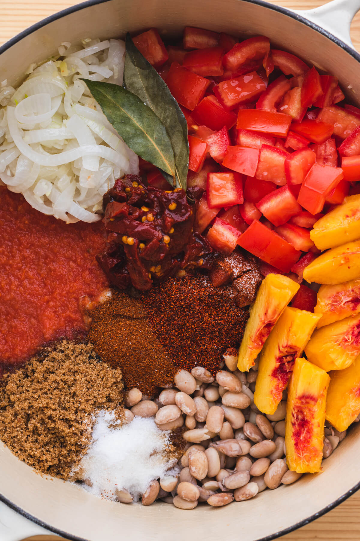 Close up of all the ingredients for Chipotle Pinto Beans in a Dutch oven before being mixed and baked.
