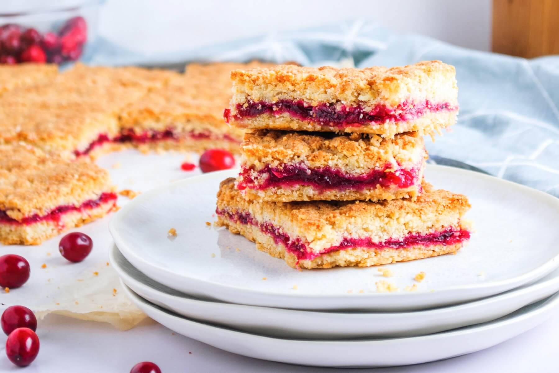 A stack of baked layered Cranberry Bars on a white plate.