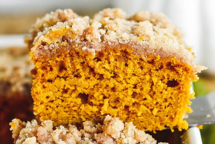 A square of fluffy orange pumpkin coffee cake topped with streusel on a plate.