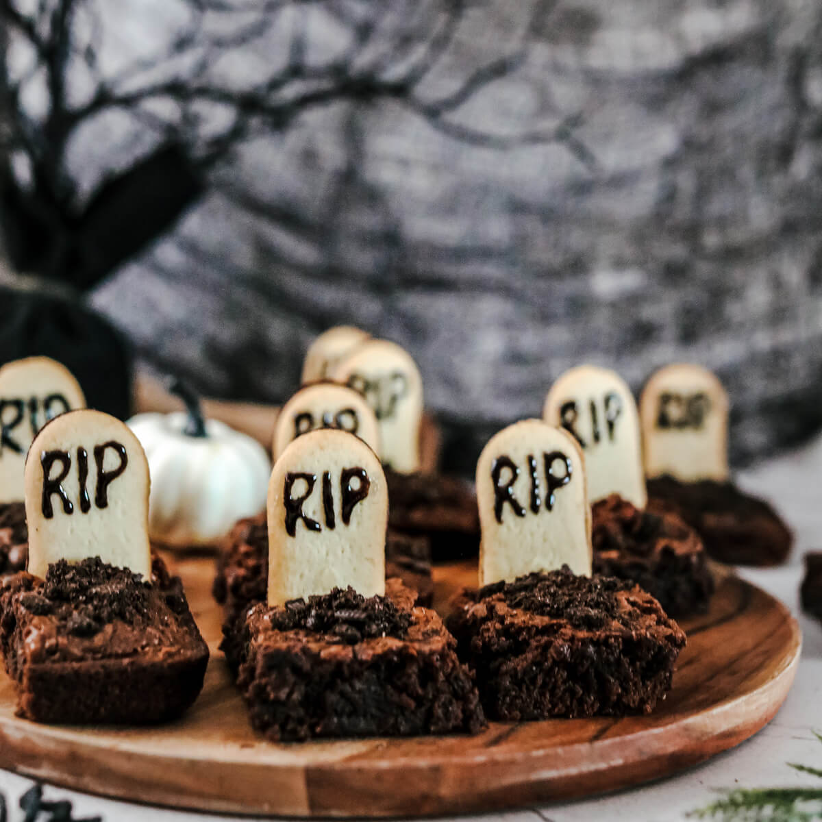 Graveyard Halloween Brownies decorated with tombstones and oreo dirt in a graveyard setting.