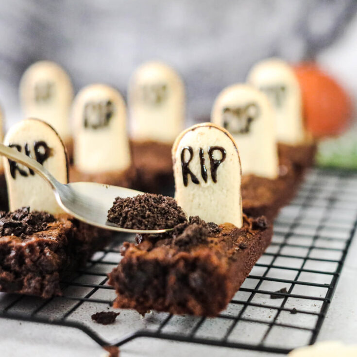 Graveyard Halloween Brownies decorated with tombstones and oreo dirt on a wire cooling rack.