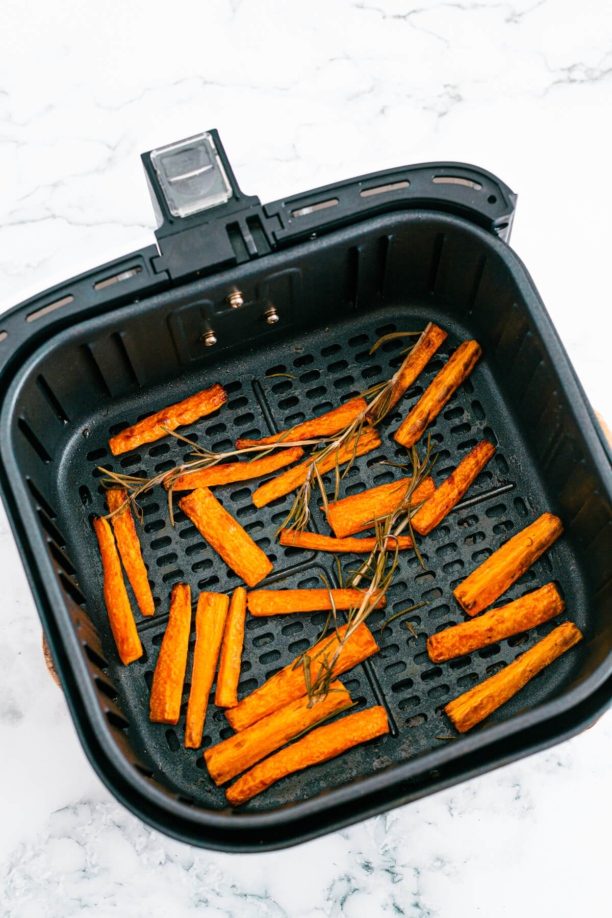 Roasted carrots in an air fryer basket.