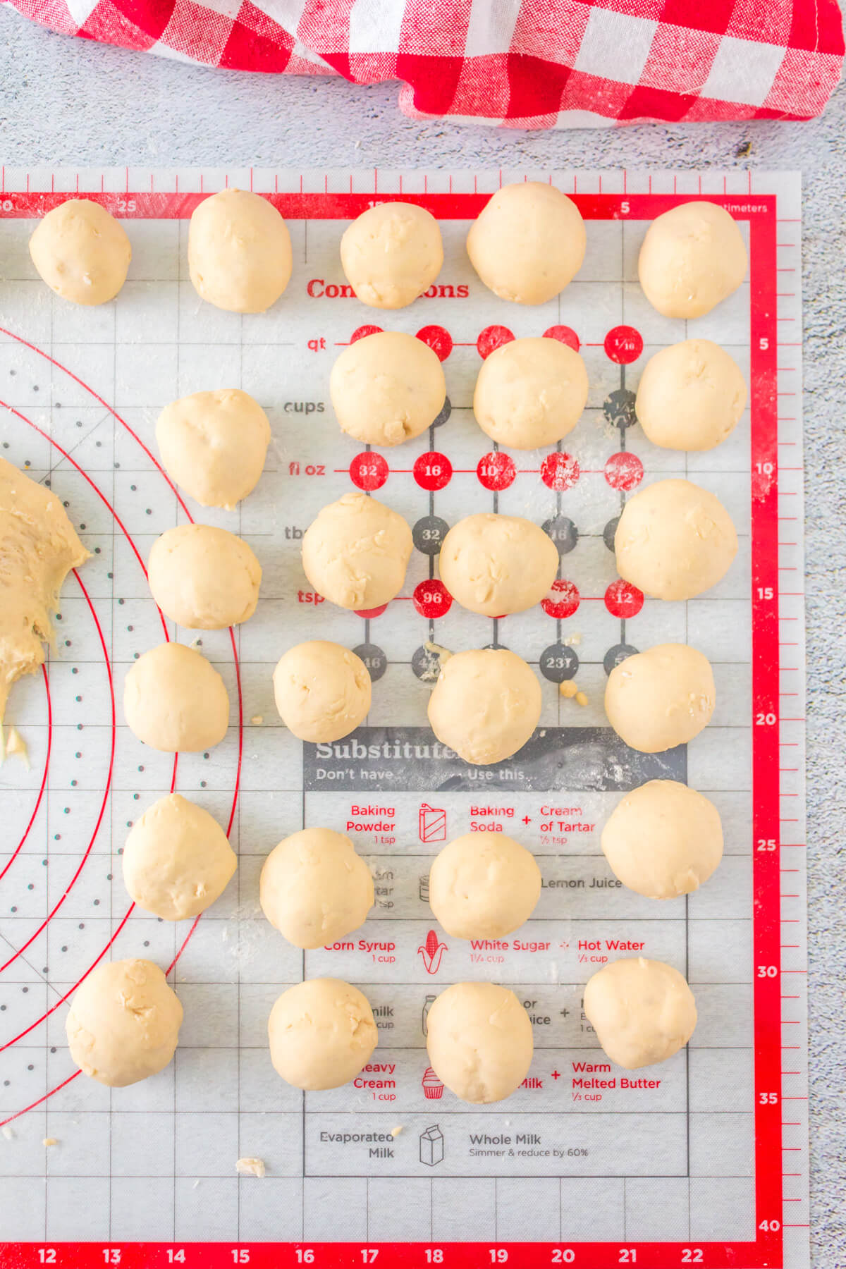 A baking mat with several dough balls of the same size.