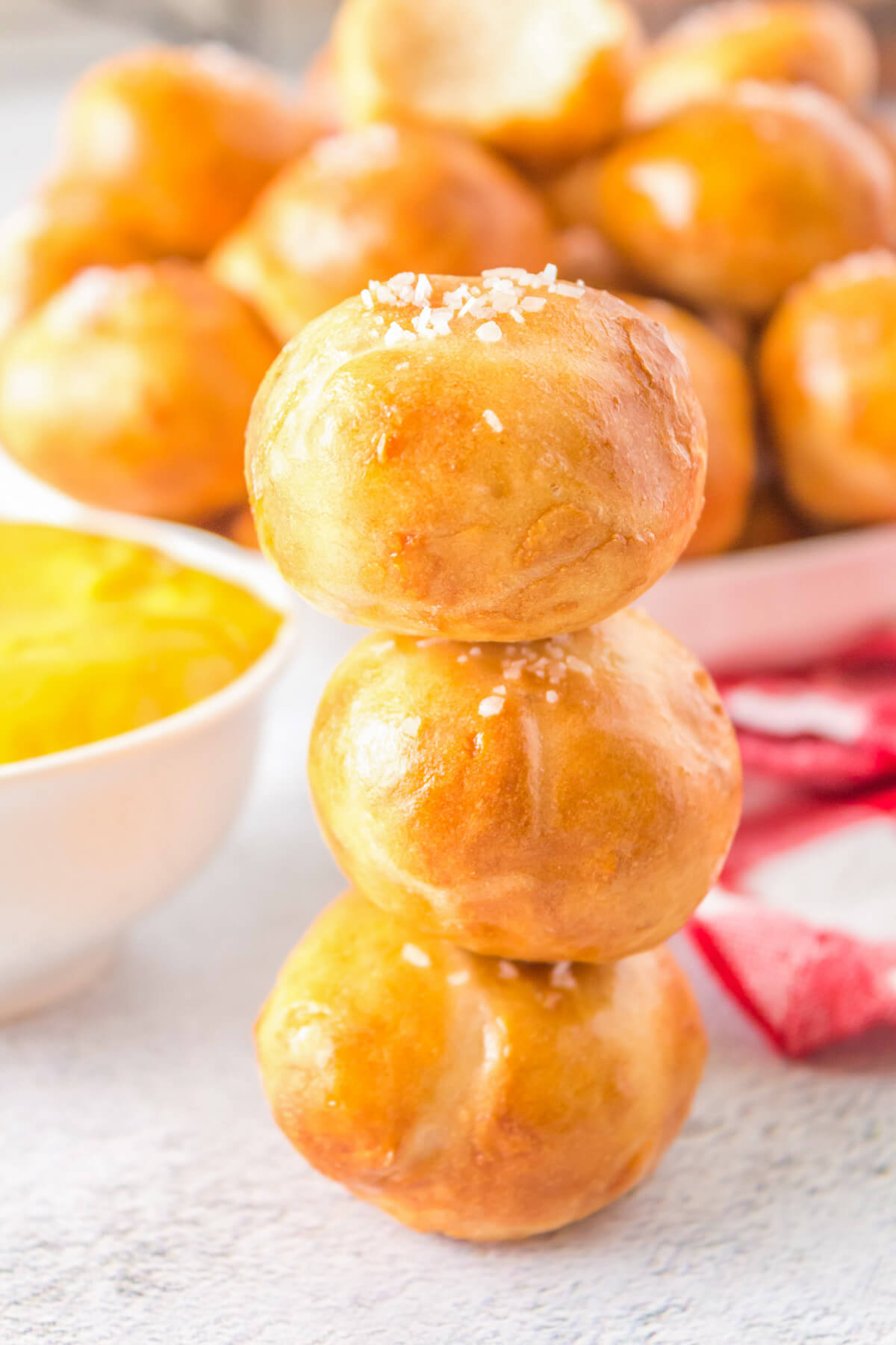 A stack of golden baked pretzel bites beside a bowl of yellow mustard.