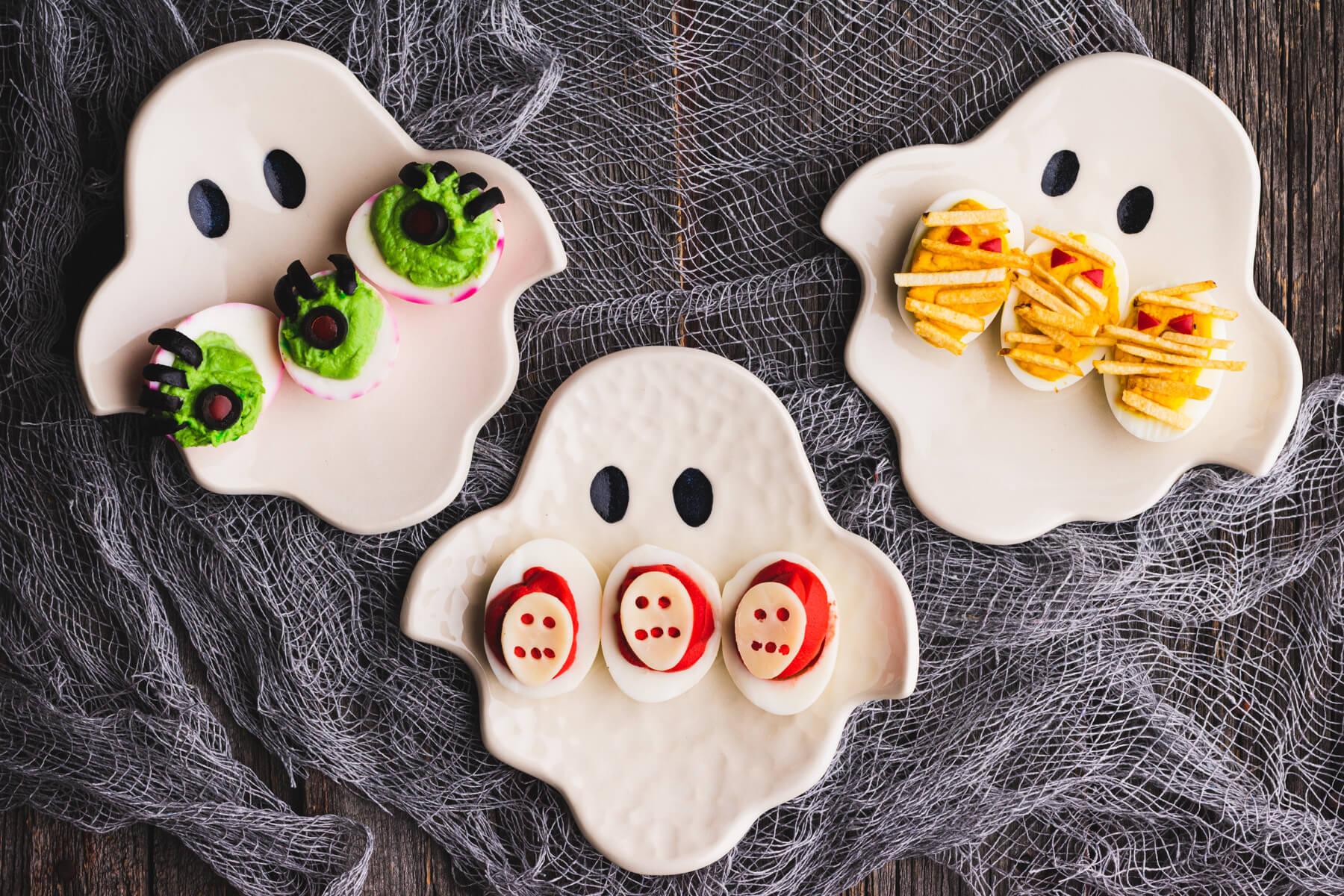 Three ghost shaped plates hold an assortment of Halloween deviled eggs.