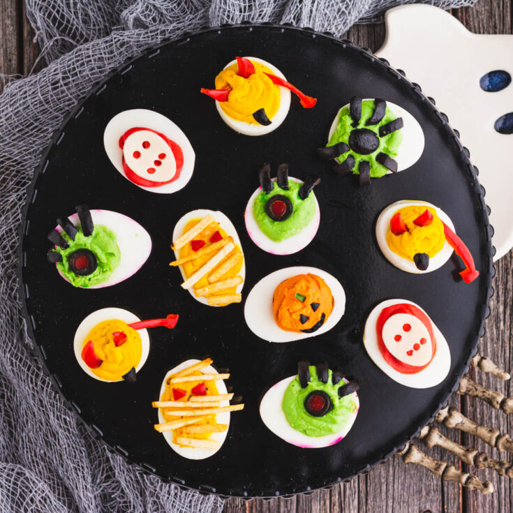 A black platter holds an assortment of creepy Halloween deviled eggs.