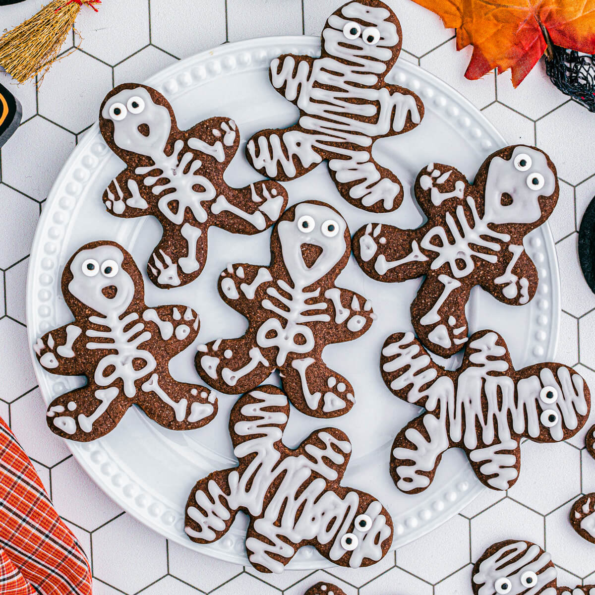 A plate of Chocolate Halloween Sugar Cookies decorated as mummies and skeletons.