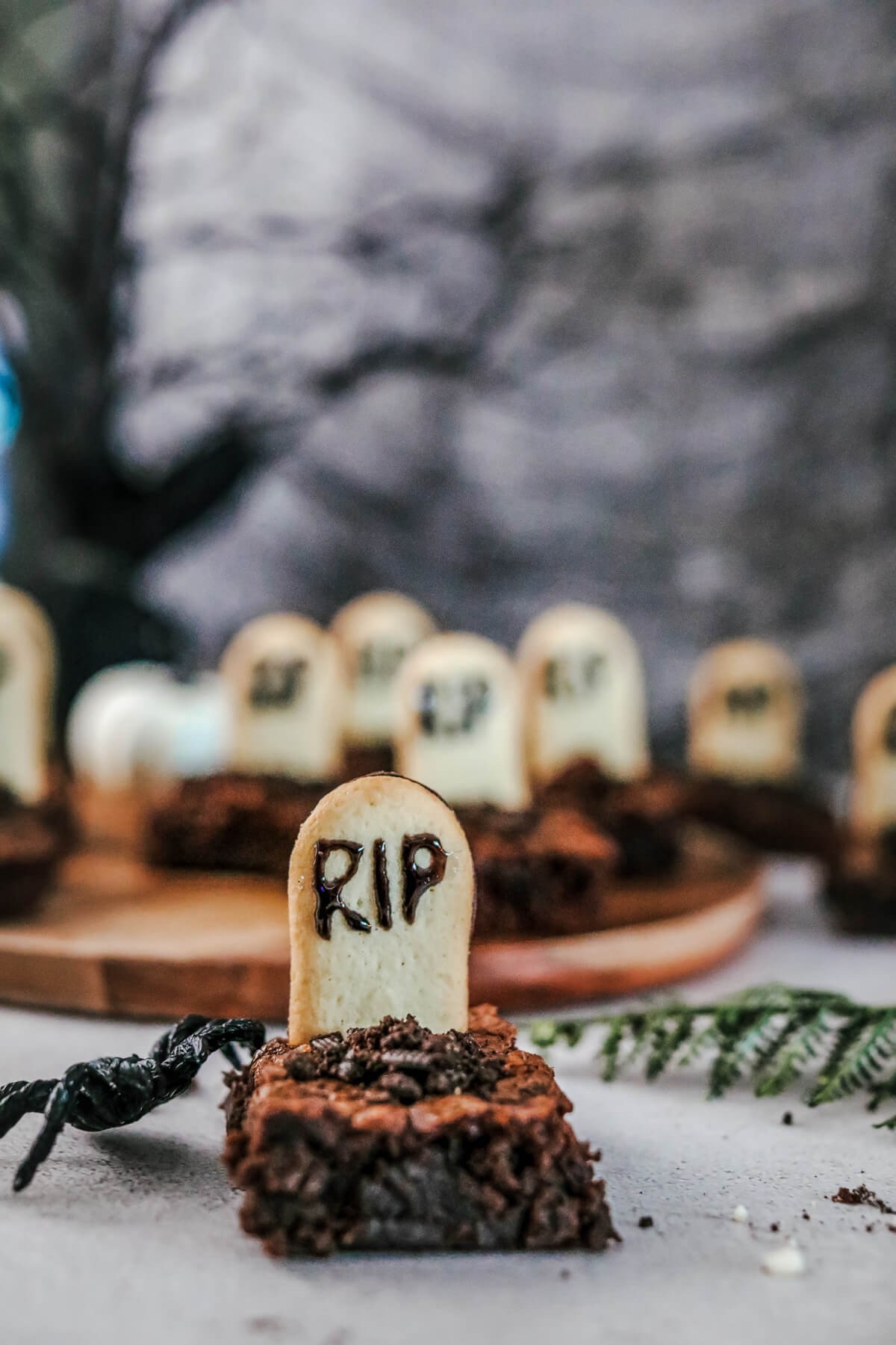 Graveyard Halloween Brownies decorated with tombstones and Oreo crumb dirt in a graveyard setting.