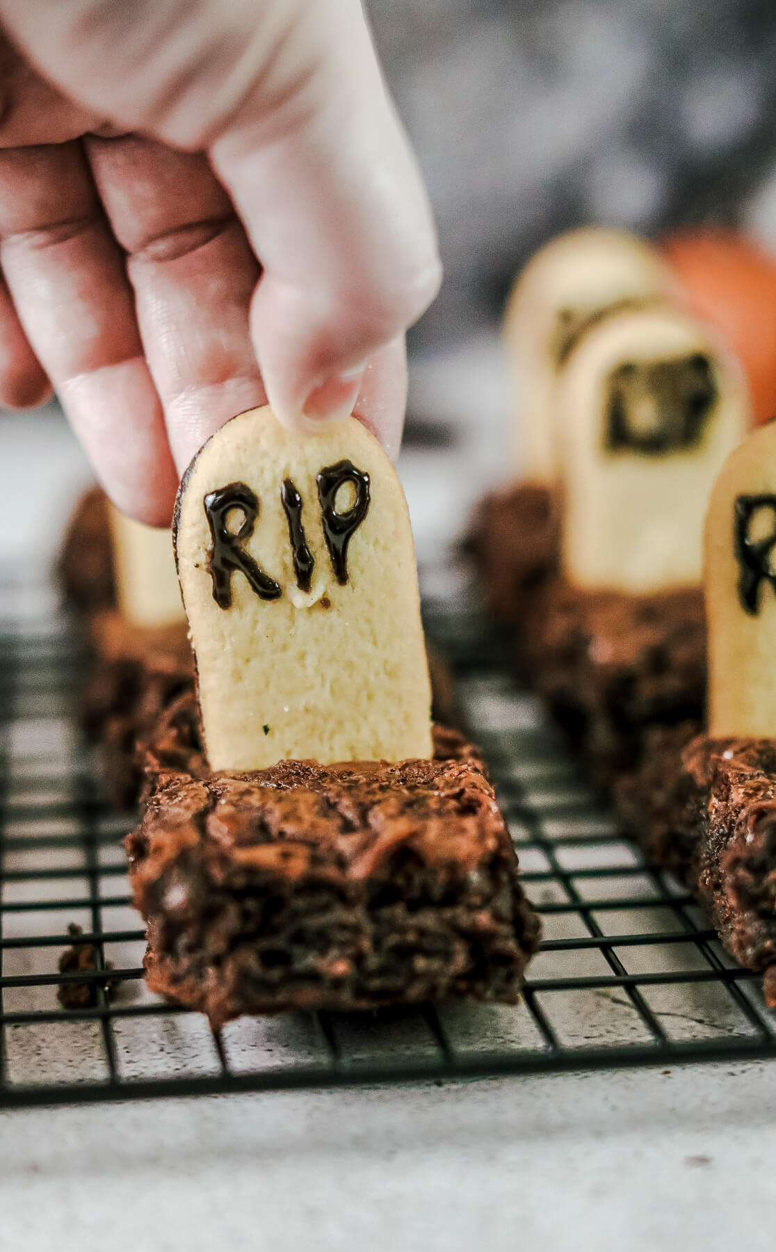 A hand placing a Milano cookie tombstone into a brownie.
