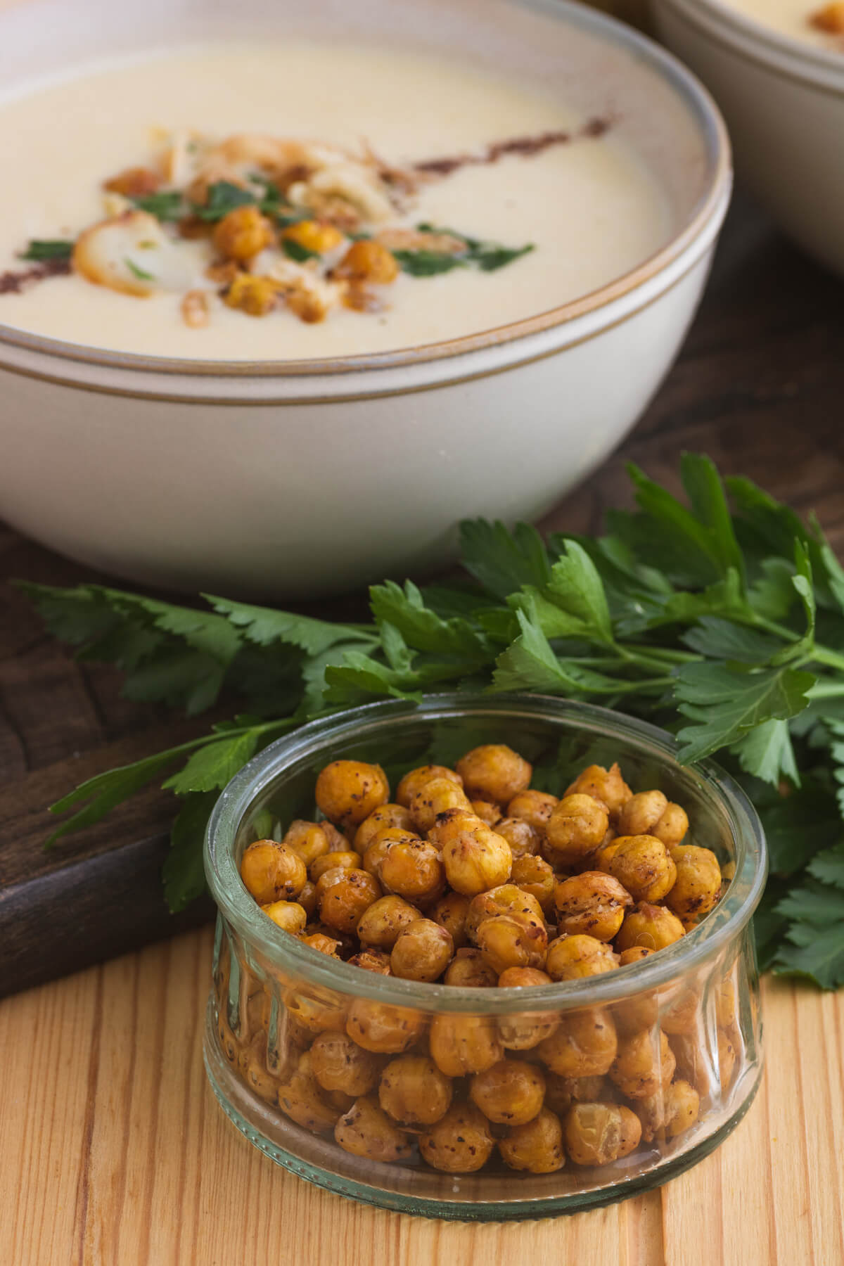 A bowl of golden roasted chickpeas in front of a bowl of chickpea soup.