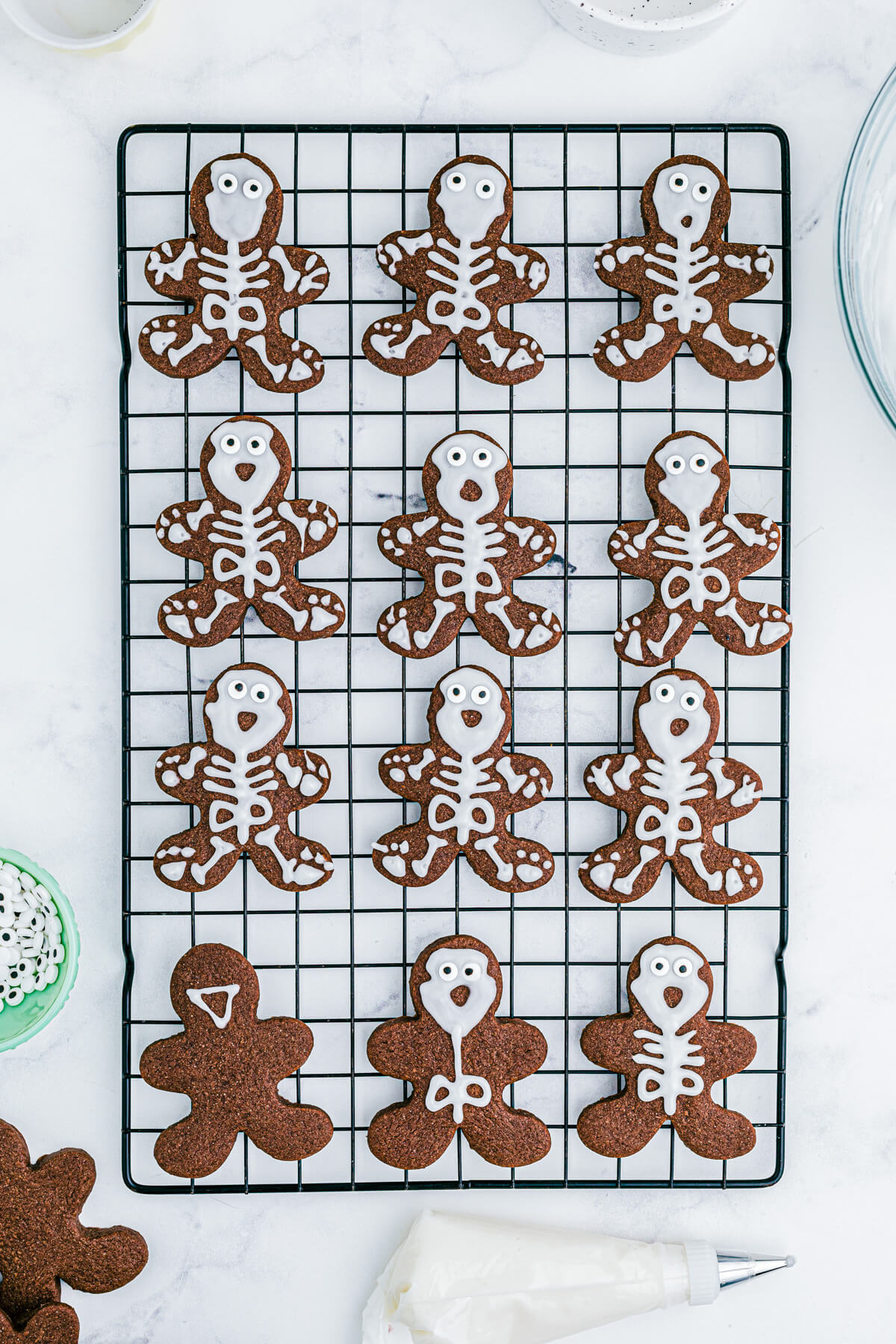 Chocolate Halloween Sugar Cookies in various states of decoration on a wire cooling rack.