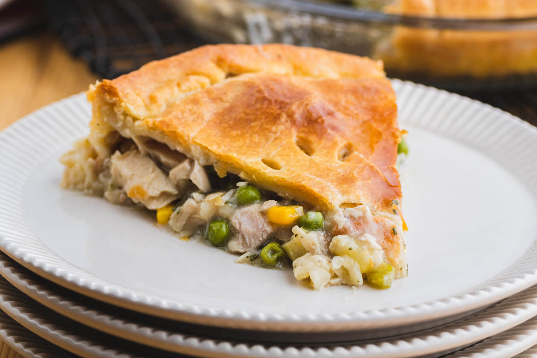 A slice of turkey pot pie on a stack of white plates.