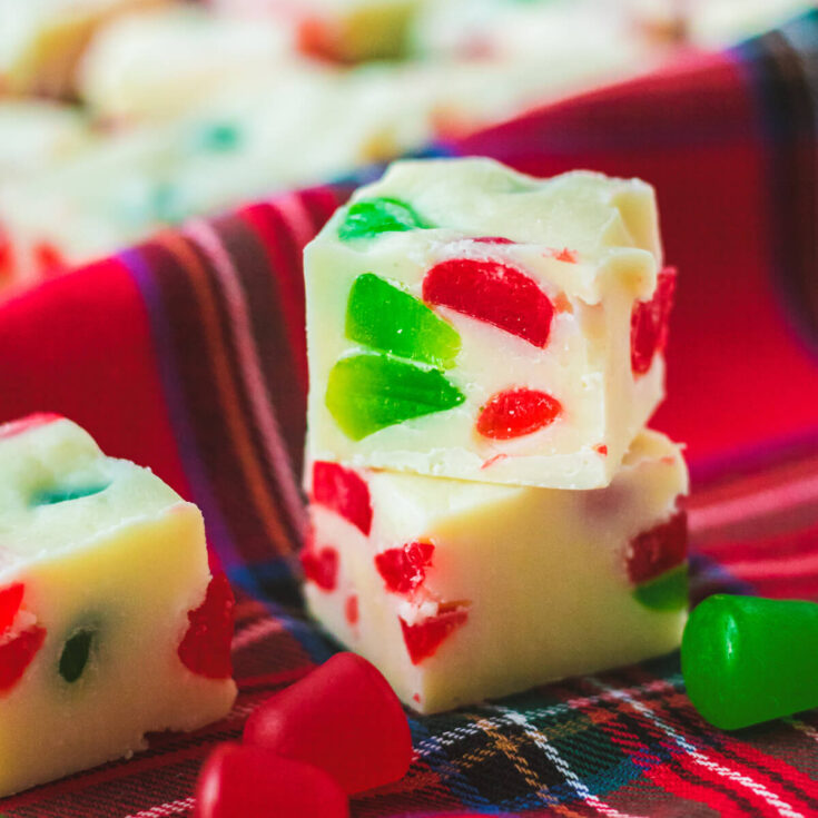 Two pieces of white fudge dotted with red and green gumdrop candies on a plaid napkin.
