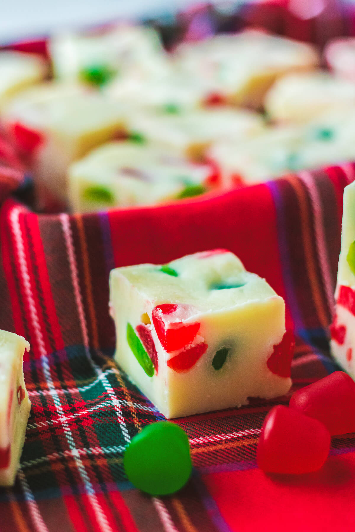A piece of white fudge dotted with red and green gumdrop candies on a plaid napkin.